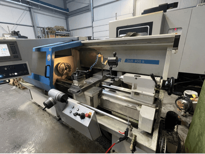 CNC-Drehmaschine DUS 400 ti in der Vorderansicht mit Bedienfeld, Werkzeughalter und beleuchtetem Arbeitsbereich.