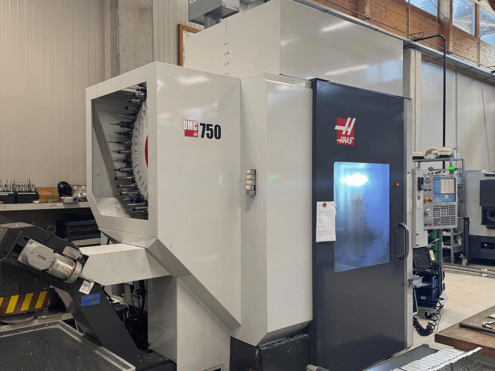 Haas UMC 750 Bearbeitungszentrum, Vorderansicht, mit Werkzeughalter und Bedienfeld in einer Werkstattumgebung.