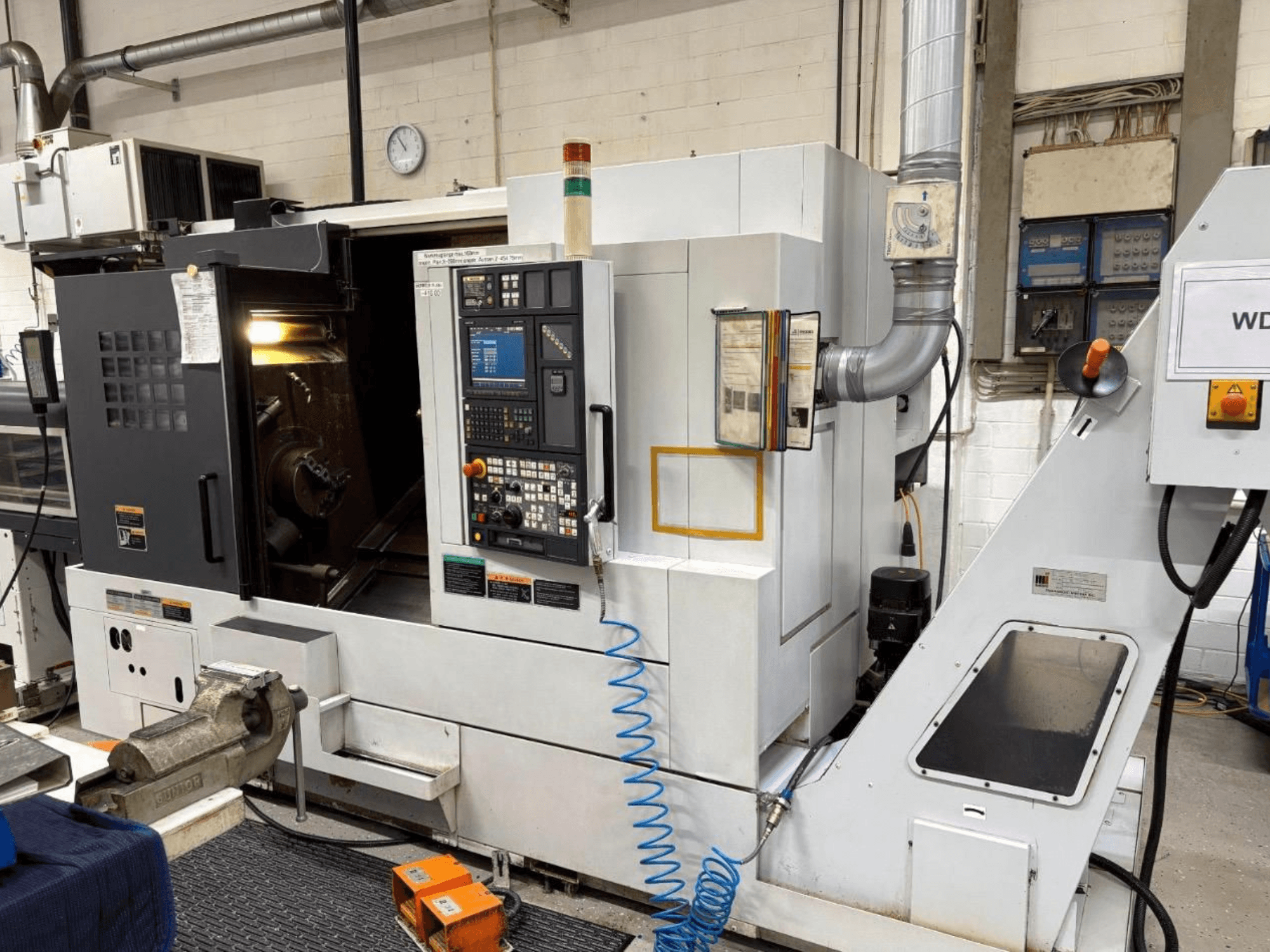MORI SEIKI NL 2500 SY Dreh-Fräszentrum, Vorderansicht, zeigt Bedienfeld und Bearbeitungsbereich. Sichtbares Kühlsystem und Zubehör.