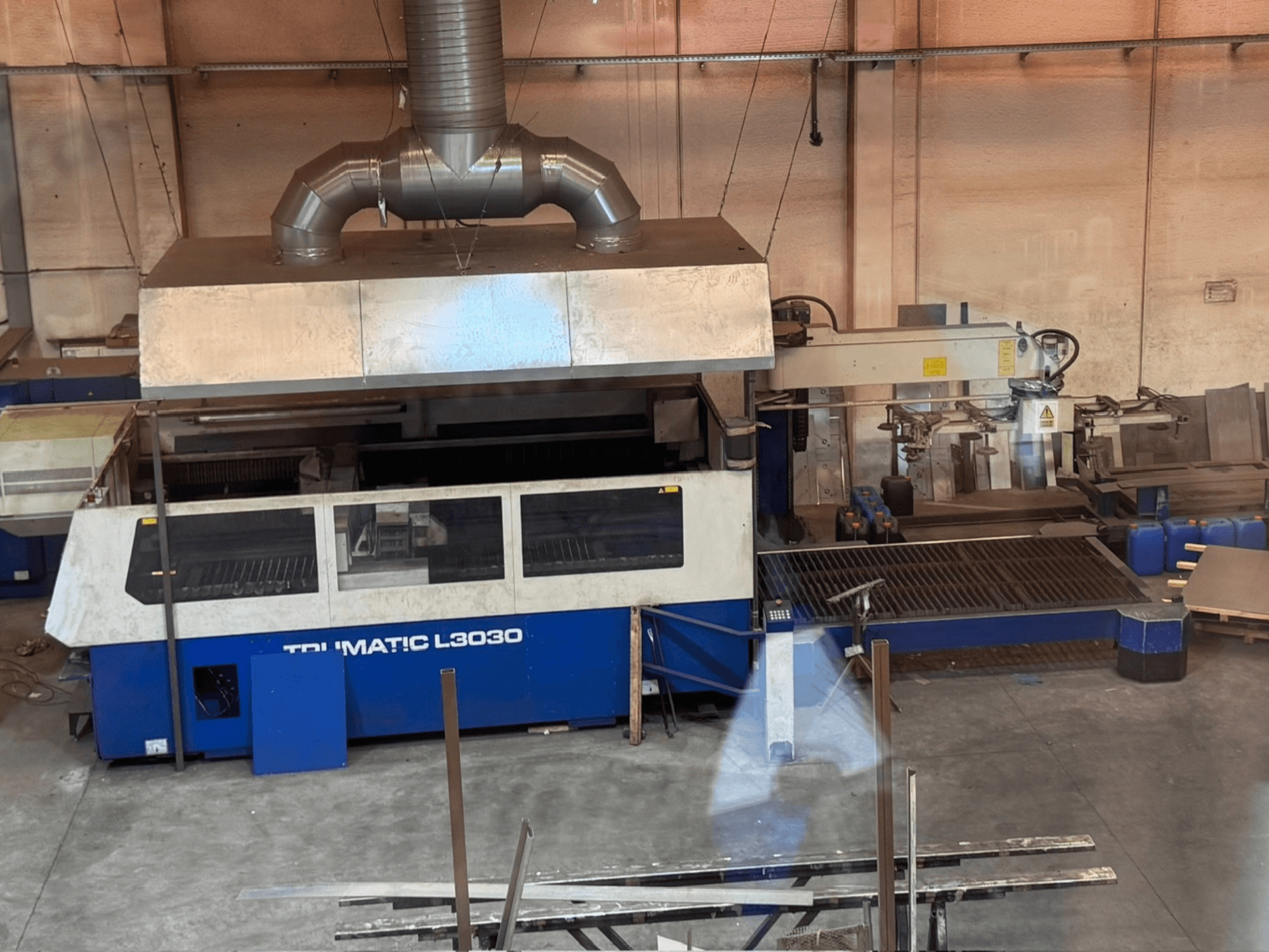CO₂-Laserschneidmaschine TRUMPF TRUMATIC L3030 in einer Werkstatt, Vorderansicht mit Bedienfeld und Schneidetisch.