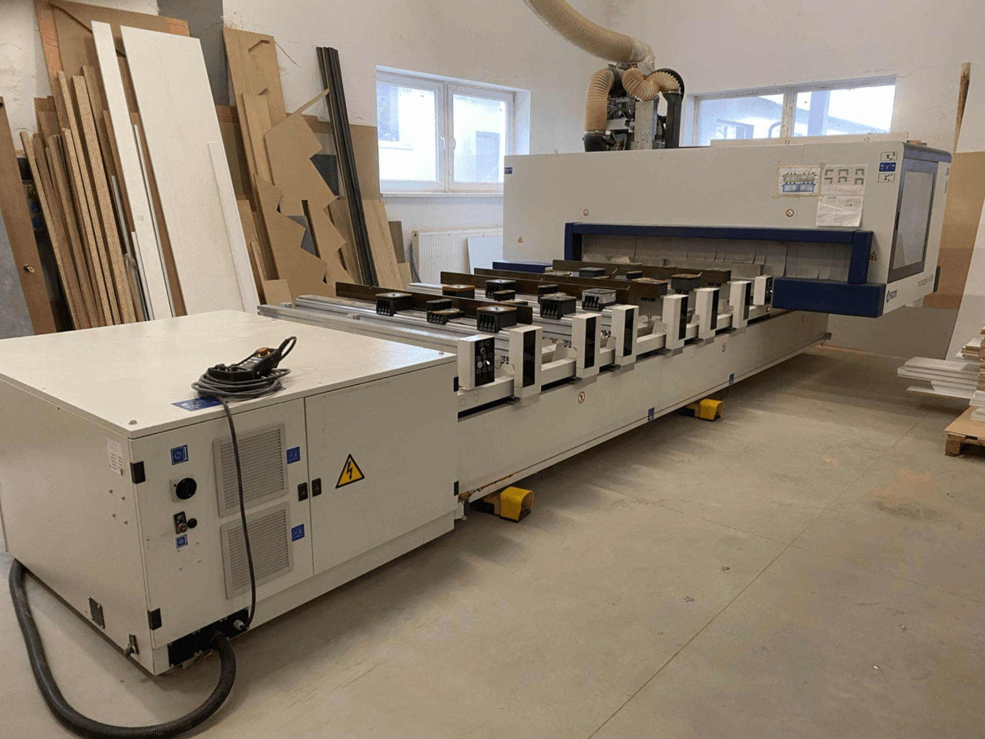 Das CNC-Holzbearbeitungszentrum M100 von SCM Morbidelli in einer Werkstatt, dargestellt in der Vorderansicht mit Bedienfeld und Staubabsaugung.