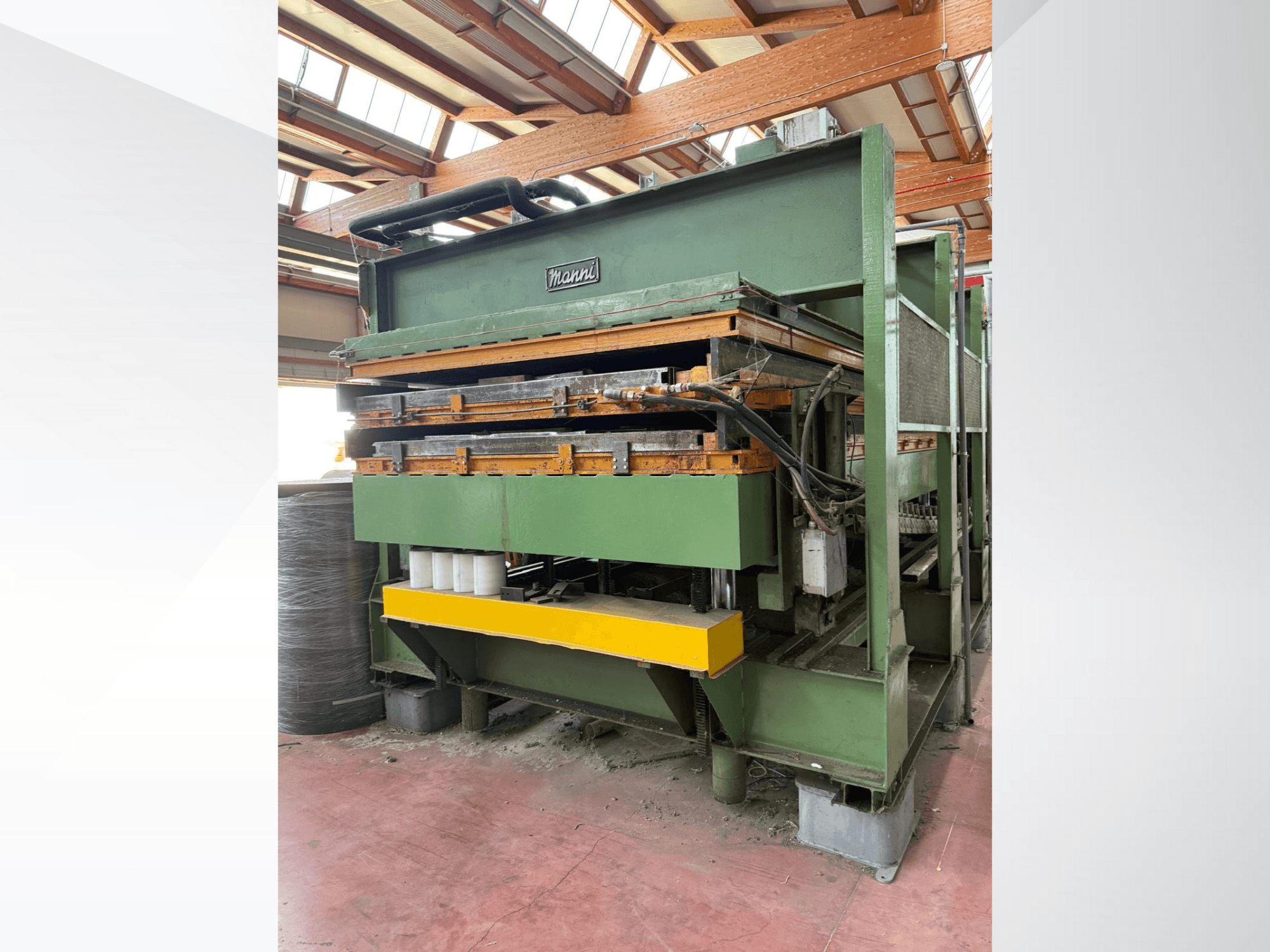 Hydraulische Presse von Manni, Seitenansicht, mit grünem Metallgehäuse, gelbem Sockel und mehreren sichtbaren Hydraulikleitungen.