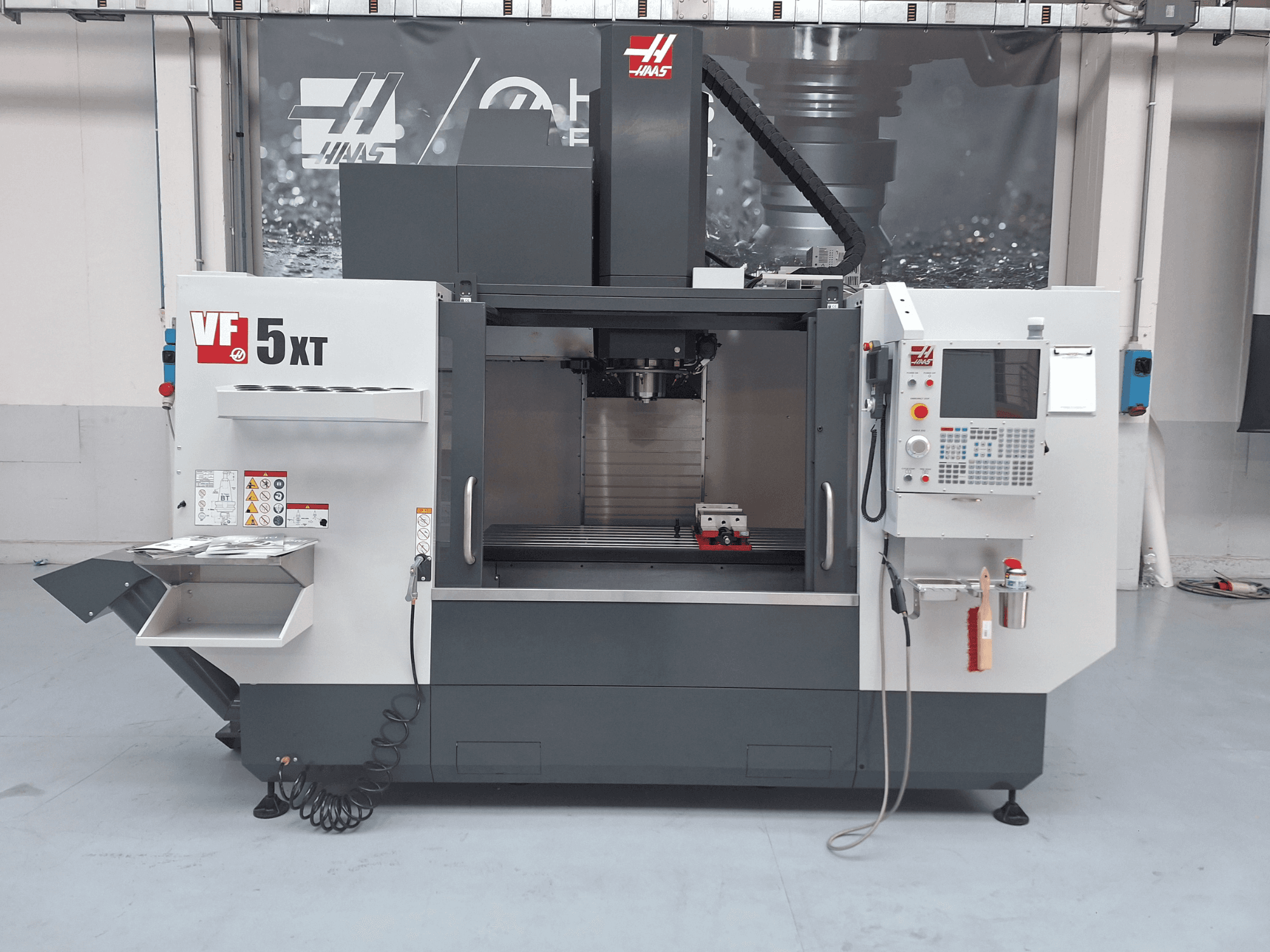 Vertikales Bearbeitungszentrum HAAS VF-5/50XT, Vorderansicht, mit Blick auf das Bedienfeld, den Spindelbereich und das Werkzeugmagazin.