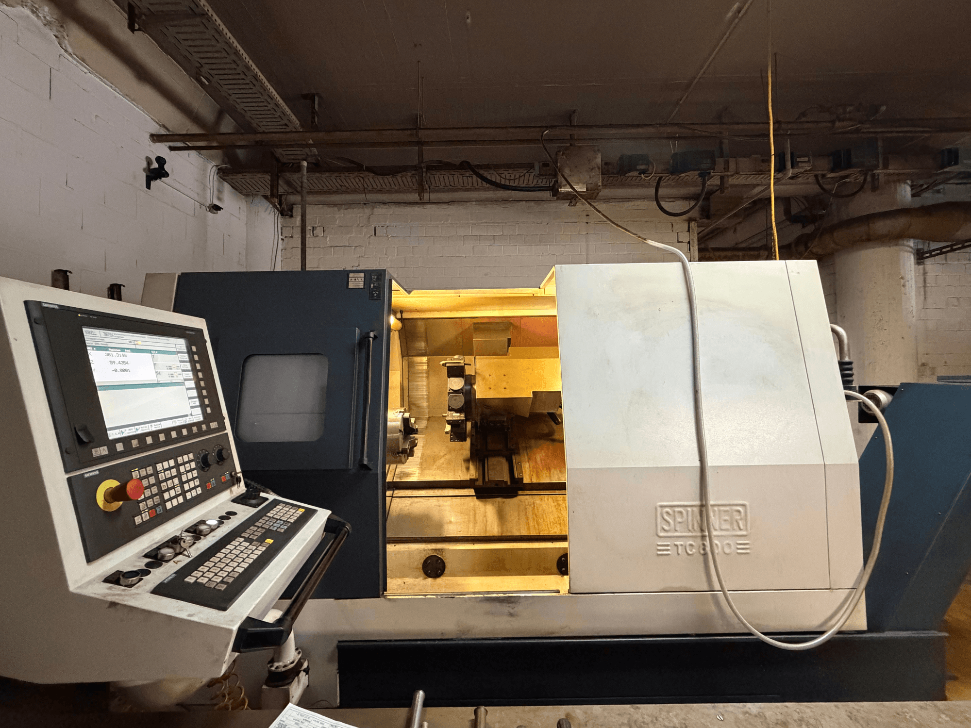 Horizontal-Drehmaschine SPINNER TC800 in einer Werkstatt, mit Bedienfeld und sichtbaren internen Komponenten.