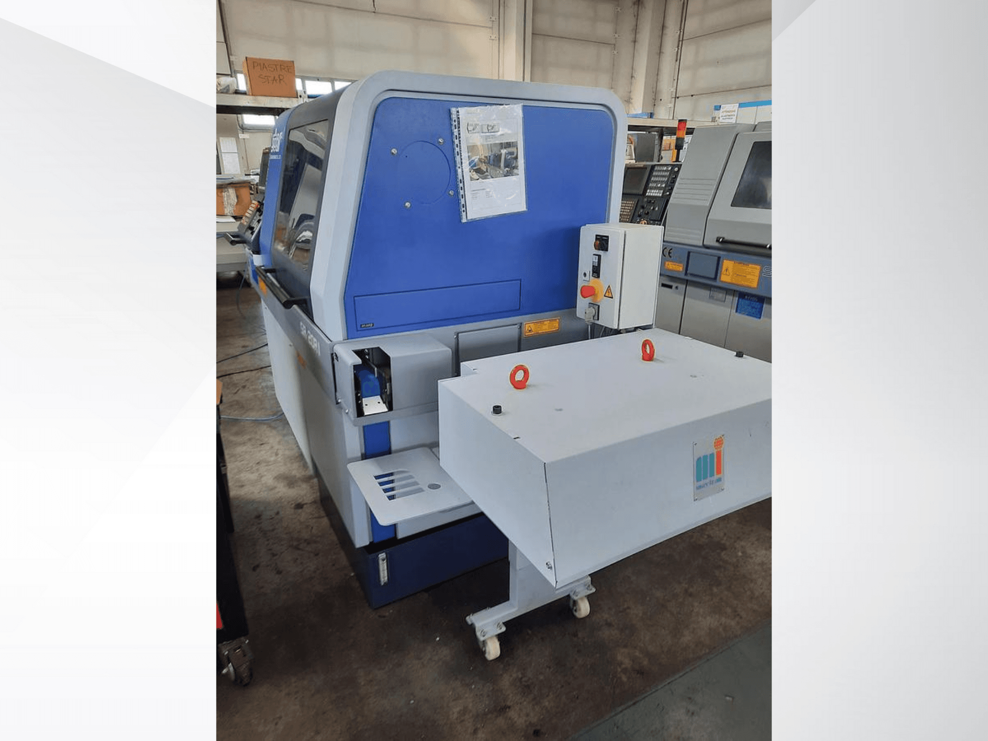 Blaue Industriemaschine mit weißem Förderband, mit Bedienfeld und angebrachten Sicherheitsvorrichtungen, Seitenansicht.