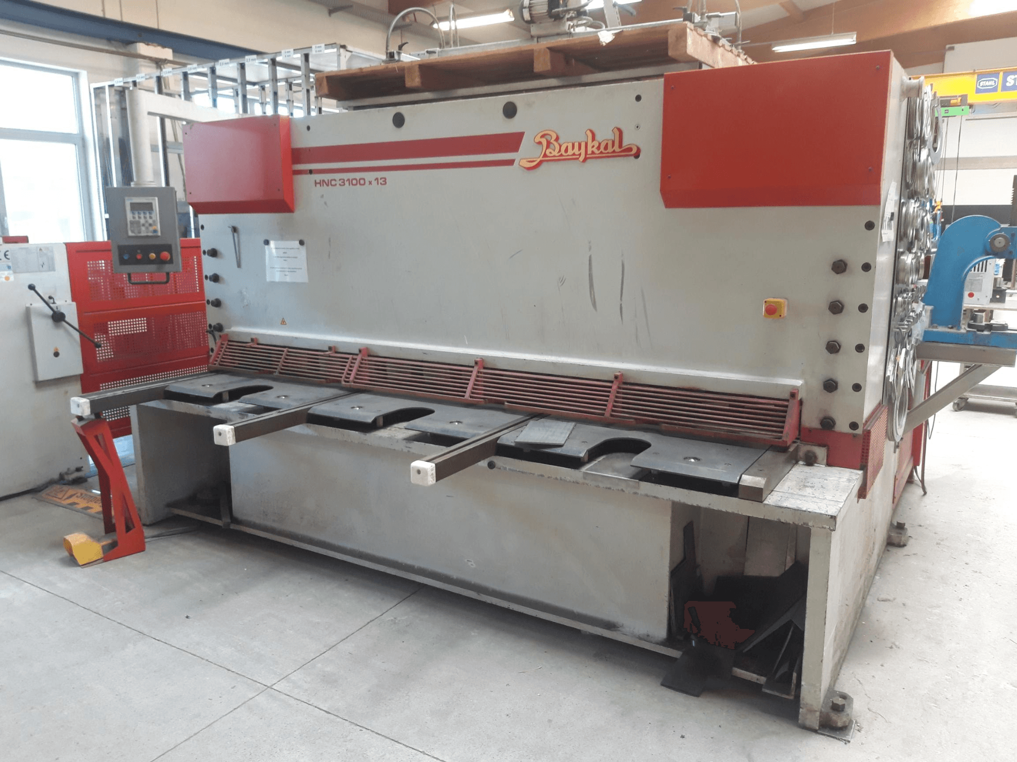 Vorderansicht der CNC-Schere Baykal HNC 3100x13 mit Bedienfeld, Schneidbereich für Metall und Auffangbehälter für Schrott.
