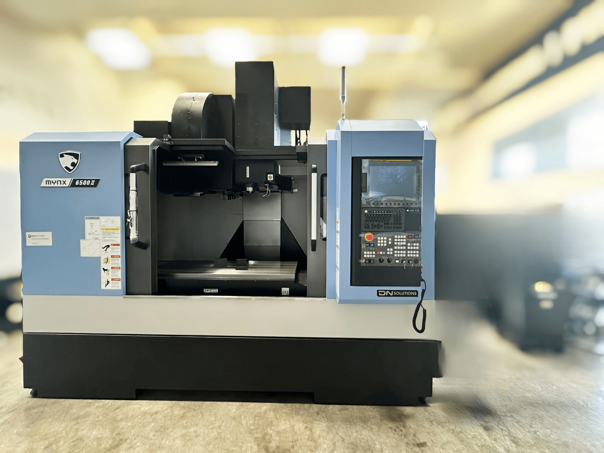 Vertikales Bearbeitungszentrum DN SOLUTIONS MYNX 6500 II, Vorderansicht mit Bedienfeld und Arbeitsbereich.