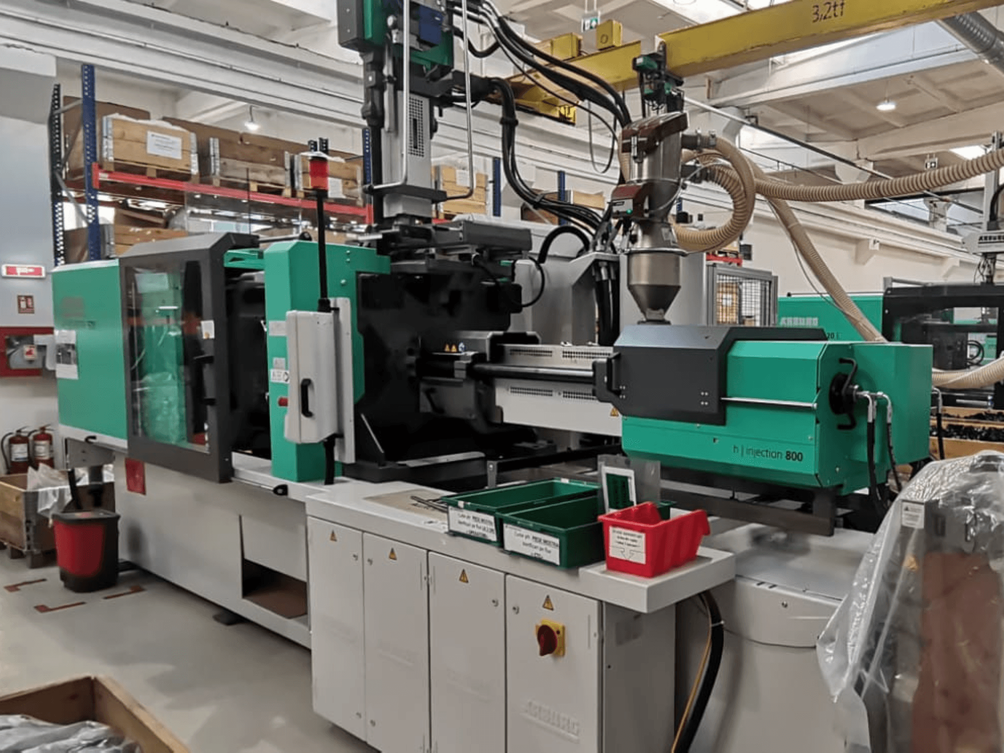H-Spritzgießmaschine 800 in einer Fabrik, Vorderansicht, in grünem und schwarzem Design, mit Bedienfeldern und Behältern für Teile.