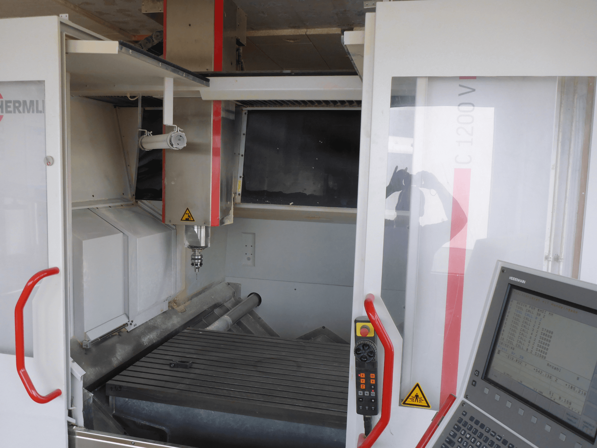HERMLE C 1200 Vertikal-Bearbeitungszentrum mit Werkzeughalter, Bedienfeld und Arbeitstisch in der Vorderansicht.
