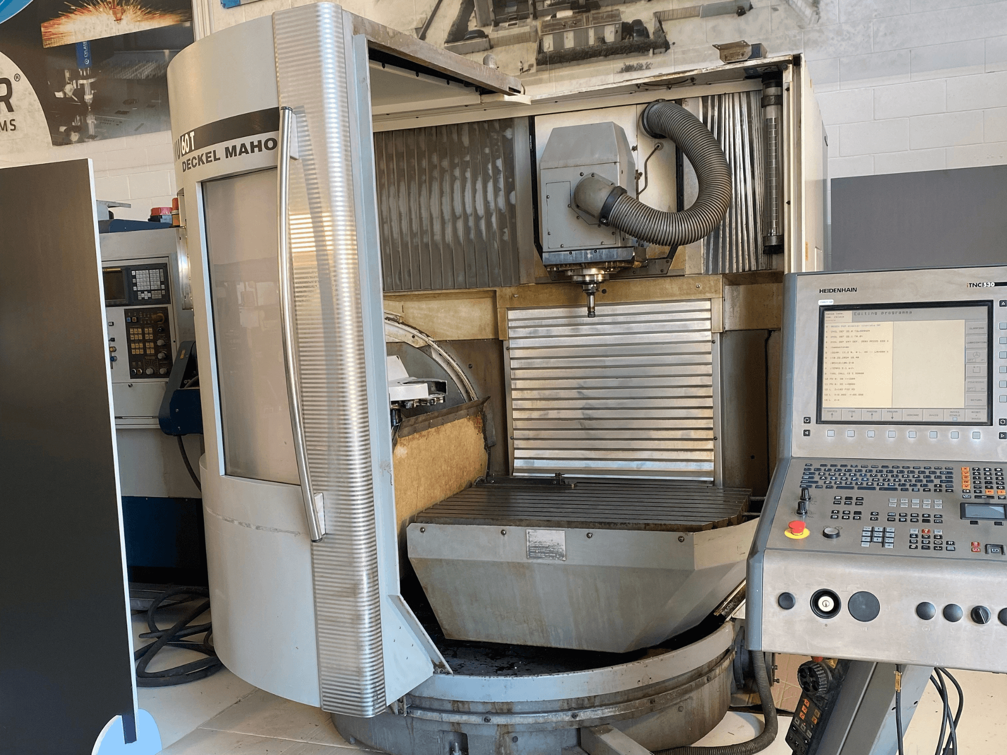 Vorderansicht einer DECKEL MAHO DMU 60T Fräsmaschine mit einem Bedienfeld, einer Spindel und einem Frästisch.