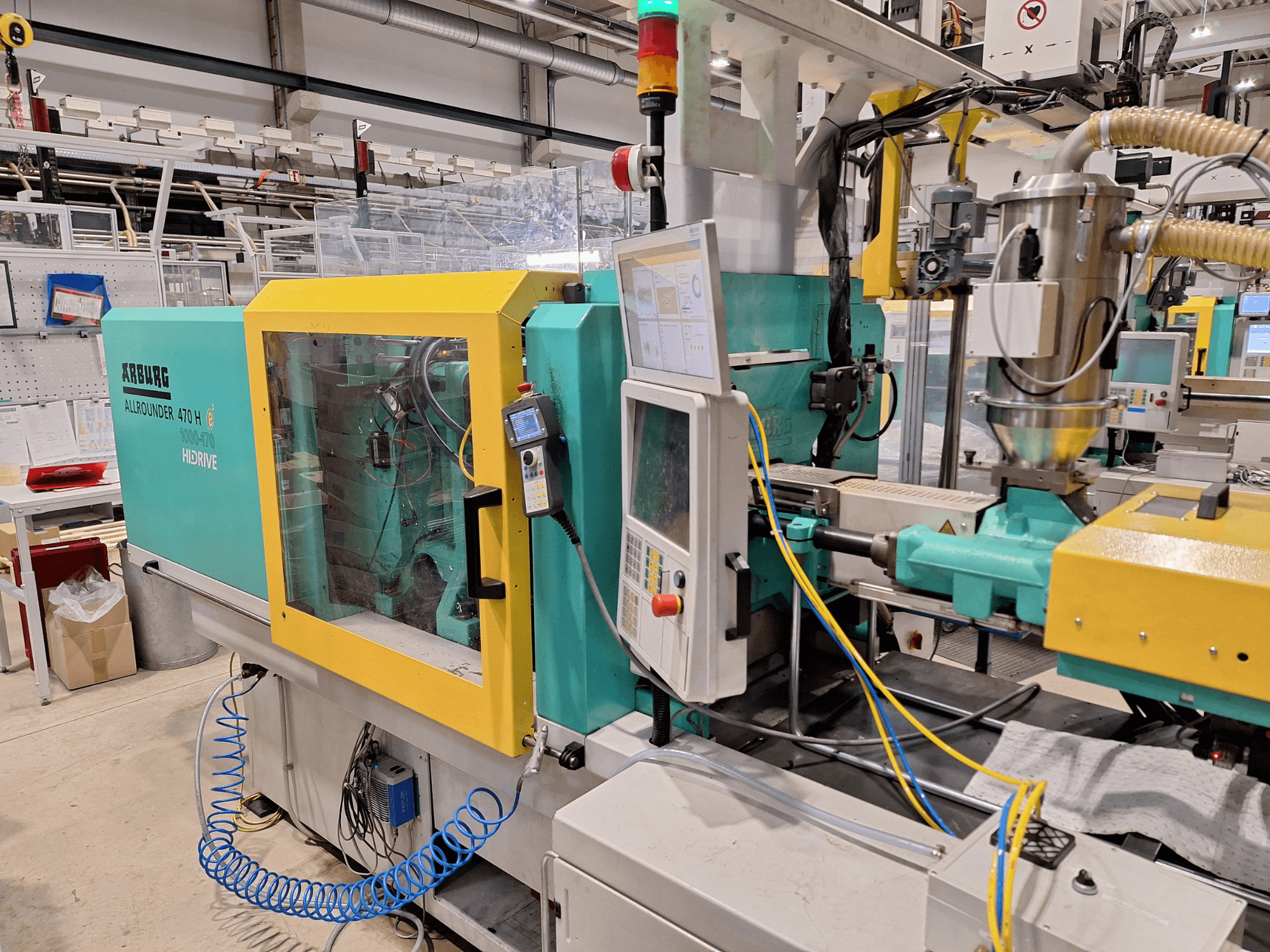 Hydraulische Spritzgießmaschine Arburg 470 H 1000-170, Seitenansicht mit Bedienfeld und Vorschubsystem.