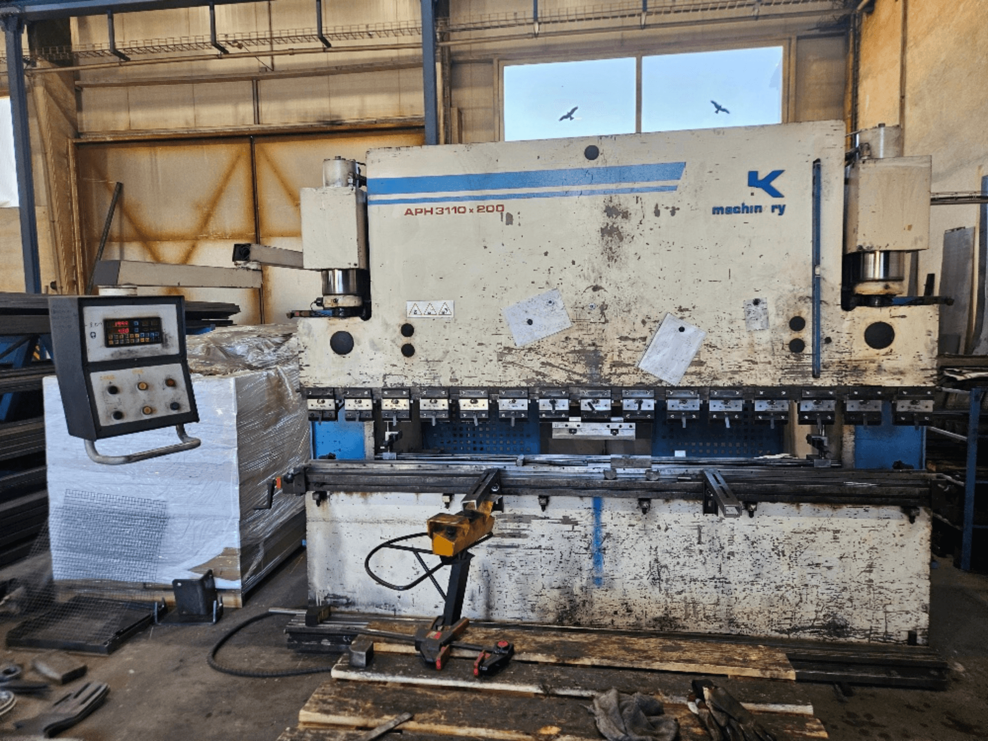 Baykal APH 3110x200 Abkantpresse in einer Werkstatt, Vorderansicht, mit Bedienfeld, Blechen und Werkzeugen sichtbar.