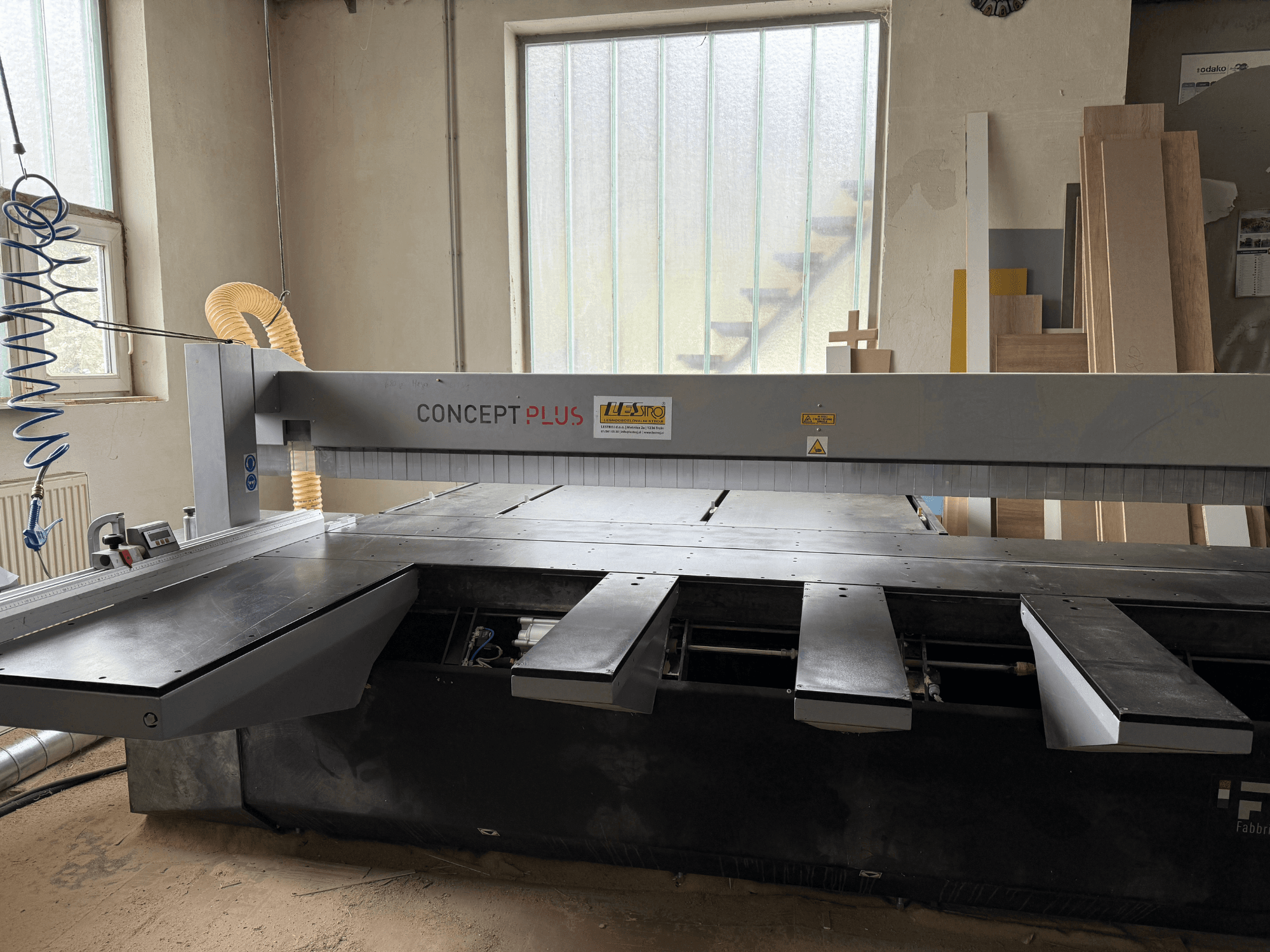 FIMAL Concept 350 Plattensäge in einer Werkstatt; Vorderansicht mit ausziehbarem Tisch und Holzplatten im Hintergrund.
