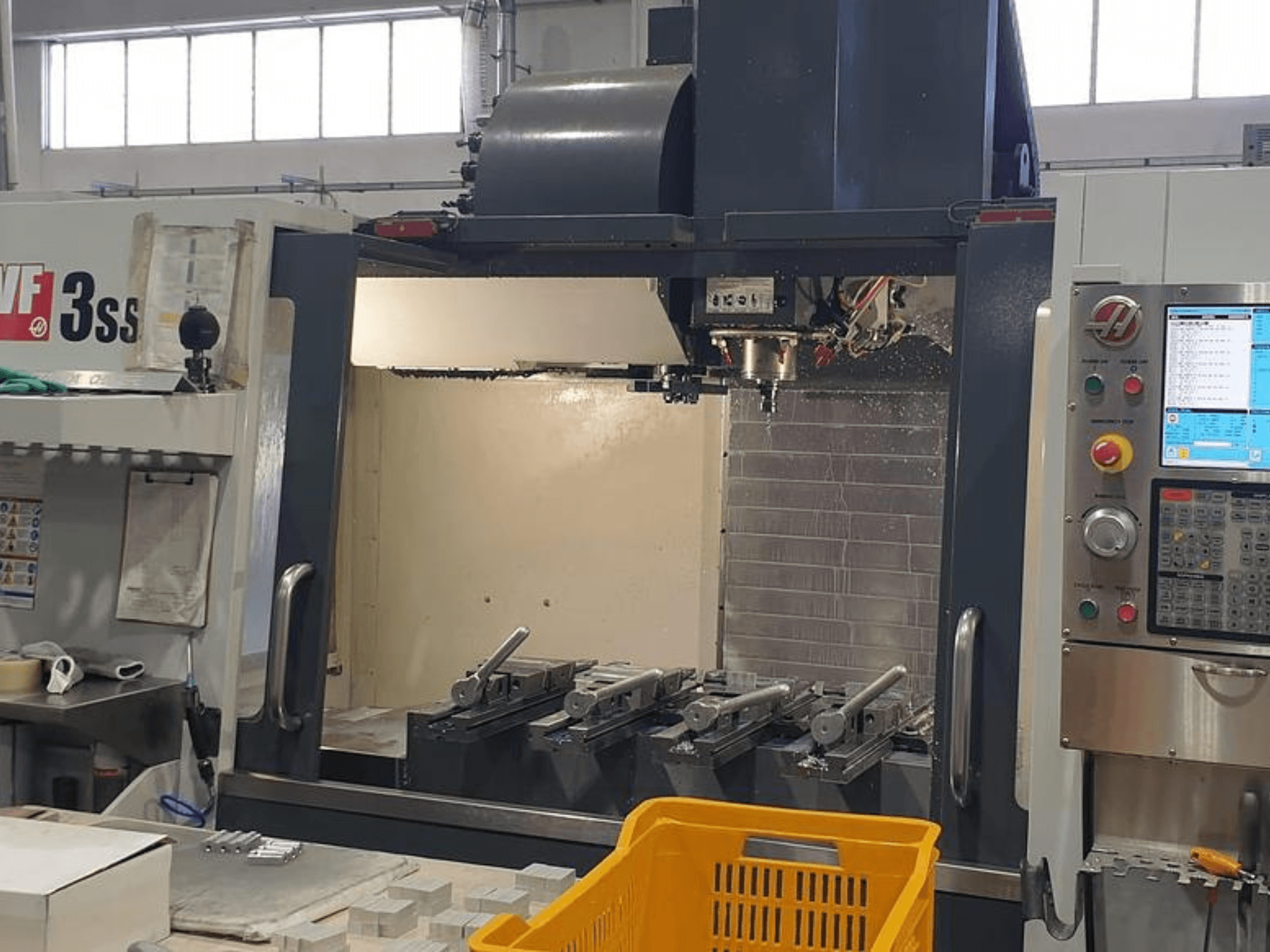 HAAS VF-3SS vertikales Bearbeitungszentrum, Vorderansicht mit CNC-Bedienfeld, Werkzeugen und orangefarbenem Korb.