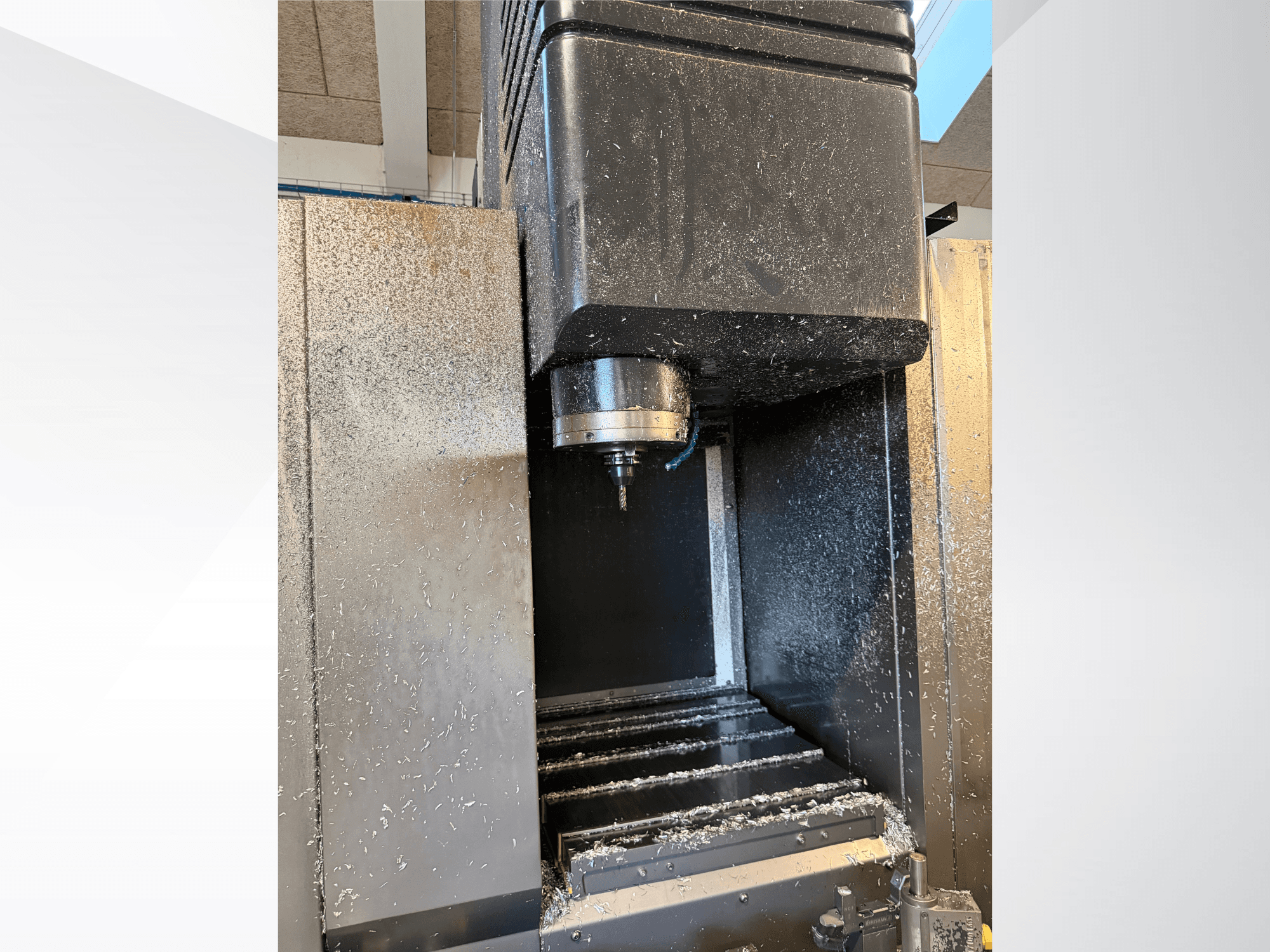 Vertikales Bearbeitungszentrum Mazak VTC 300C II, Vorderansicht, mit Spindel und Spänen aus dem Bearbeitungsprozess.