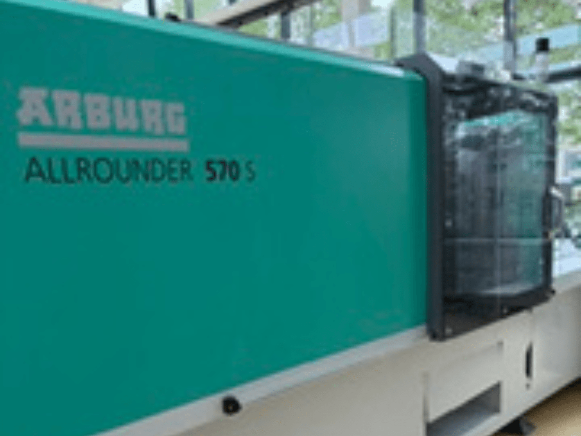 Frontansicht des Arburg ALLROUNDERs 570 S 1600-290 mit tealfarbenem Äußeren und Spritzeinheit, die einen Teil des Maschinendesigns zeigt.