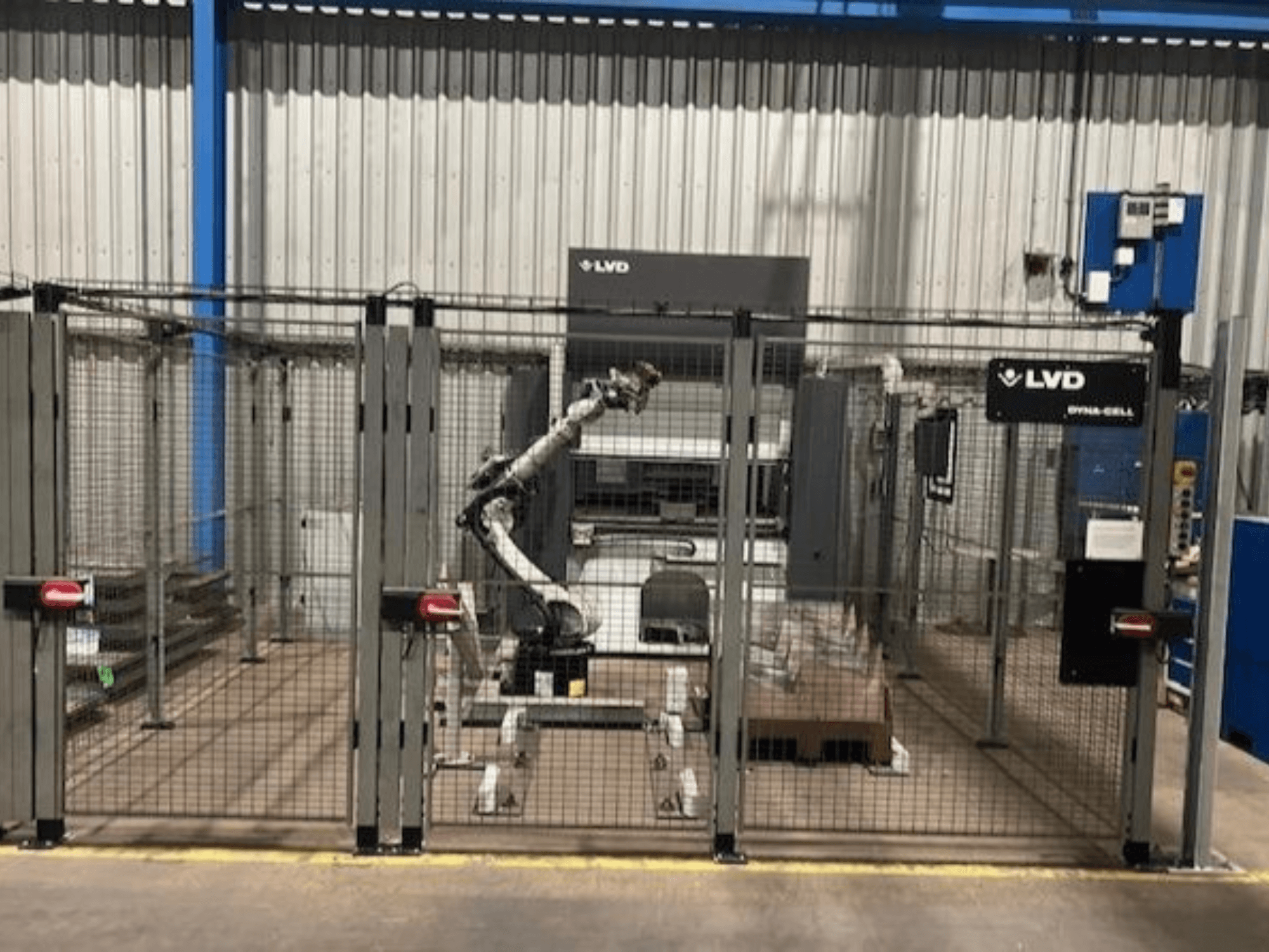 LVD Dyna-Cell-Roboterarbeitsplatz in einem umzäunten Gehäuse, Vorderansicht, mit Roboterarm und Bedienfeld.