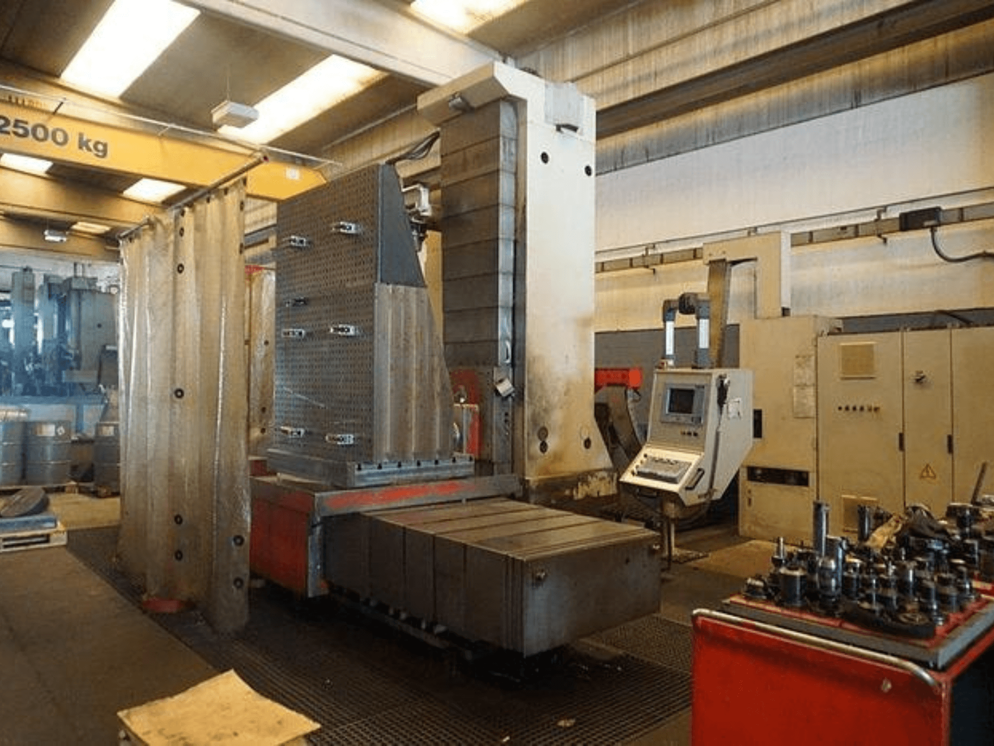 Industrielle Fräsmaschine mit Touchscreen-Steuerung und großem Arbeitstisch, von vorne gesehen in einer Werkstattumgebung.
