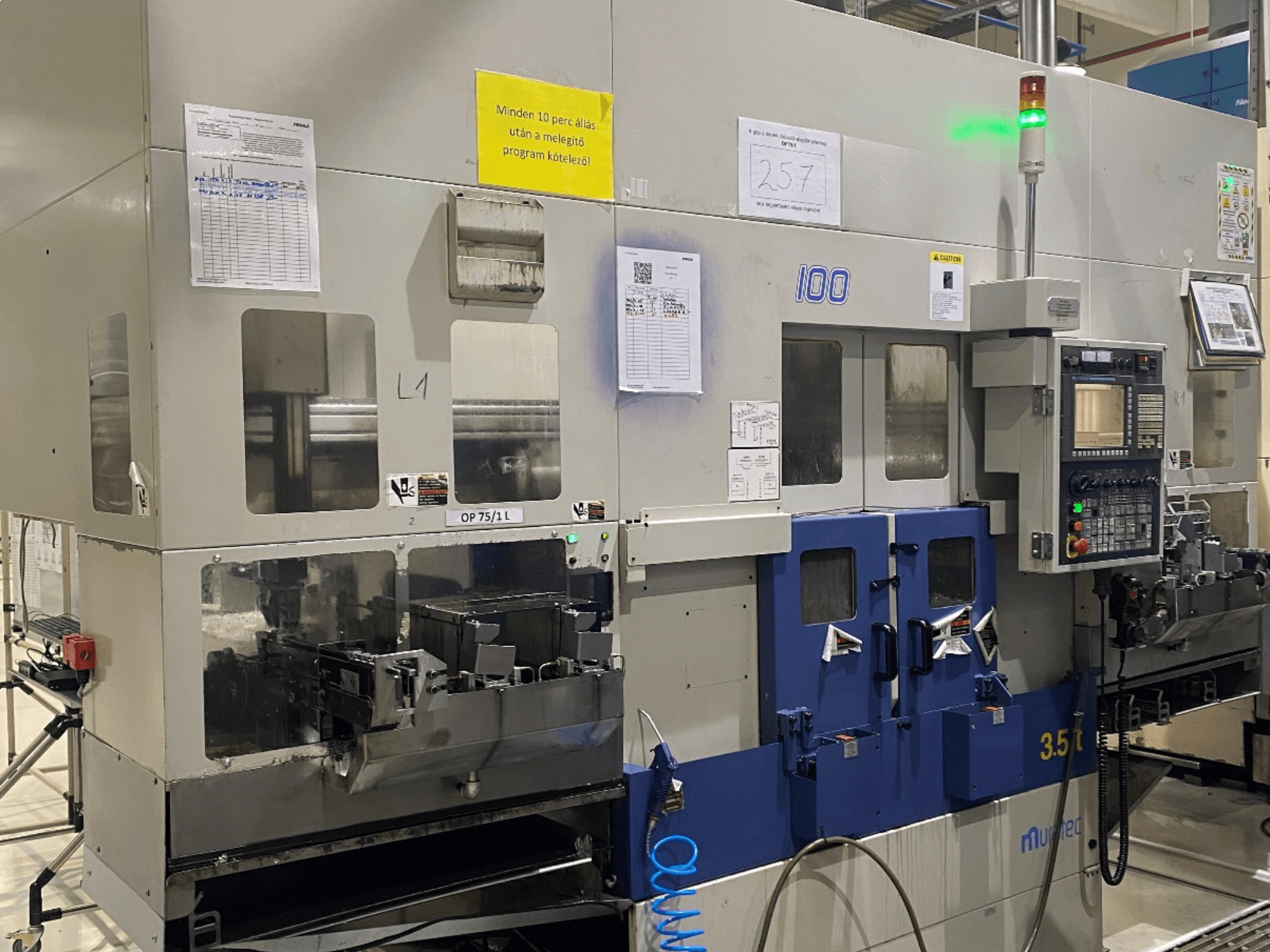 Horizontaldrehmaschine MURATA MW100 in einer Fabrikumgebung, Vorderansicht mit Bedienfeld und Betriebsdetails.