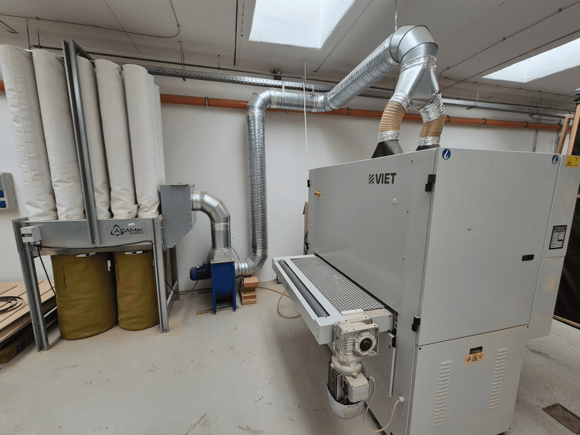 Viet Entstaubungsanlage mit zylindrischen Filtern und silbernem Auspuff, von vorne gesehen in einer Werkstatt.