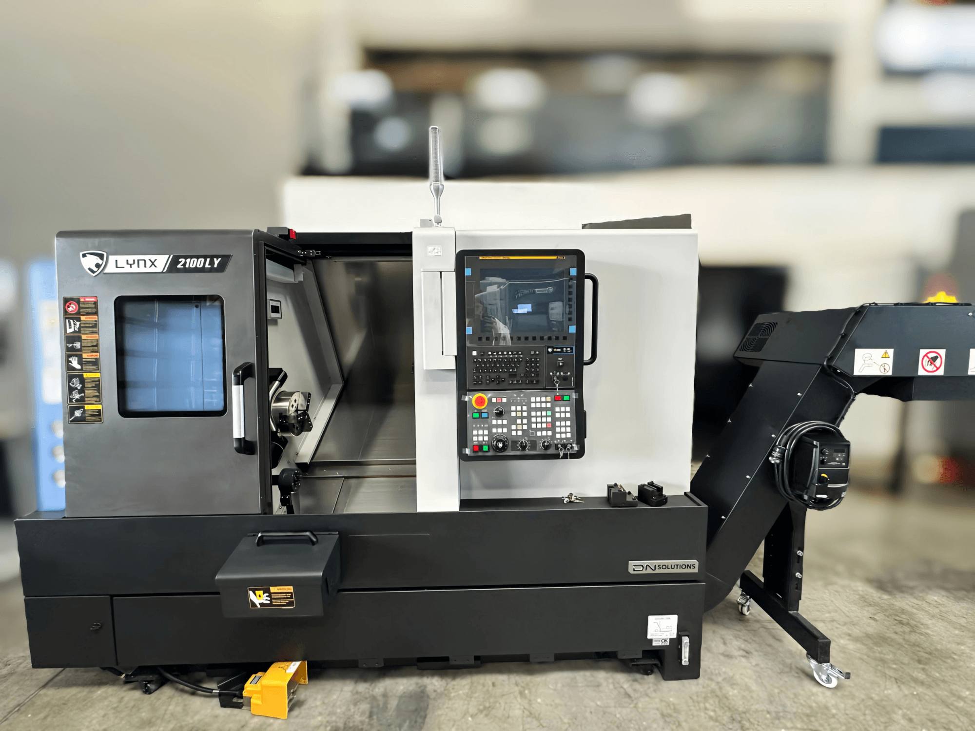 Horizontal-Drehmaschine DN SOLUTIONS LYNX 2100LYB, Vorderansicht, mit Bedienfeld und geöffneter Tür, die den Blick ins Innere freigibt.