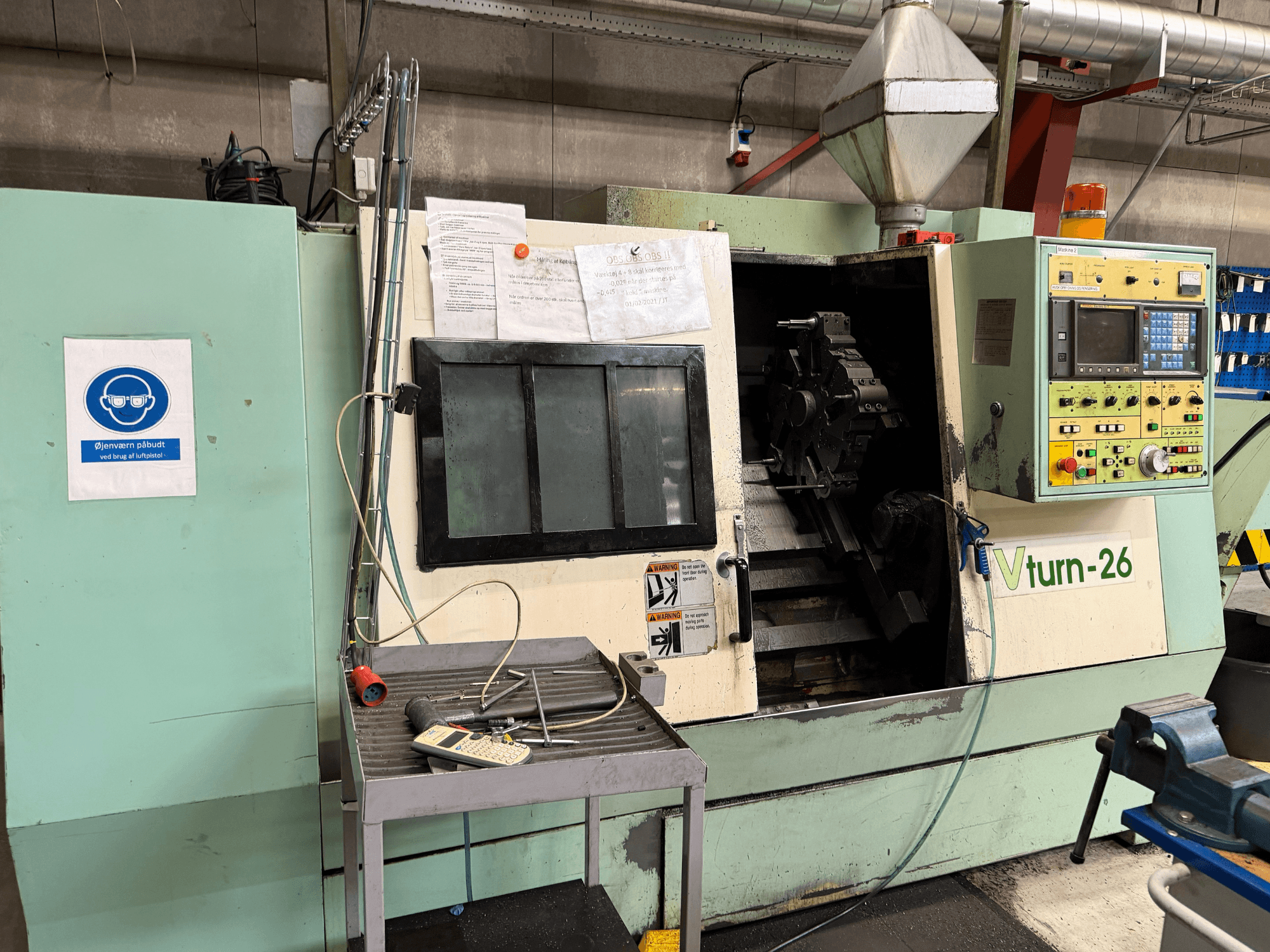 Vorderansicht der Horizontal-Drehmaschine VICTORY VTurn-26, auf der das Bedienfeld, der Arbeitsbereich und die Sicherheitsbeschilderung zu sehen sind.