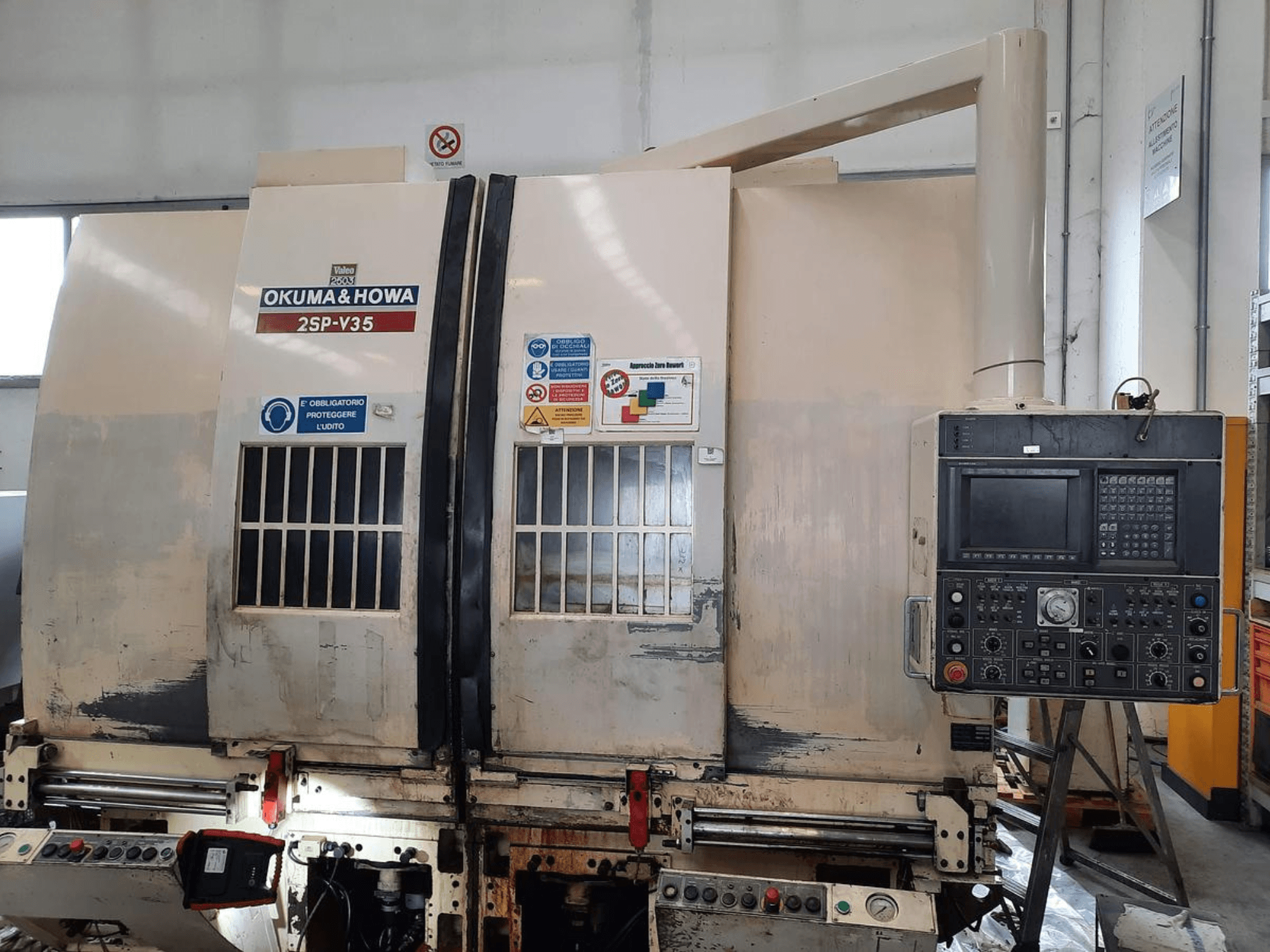 OKUMA & HOWA 2SP-V35 CNC-Maschine von vorne gesehen, mit Bedienfeld mit verschiedenen Tasten und Sicherheitsschildern.