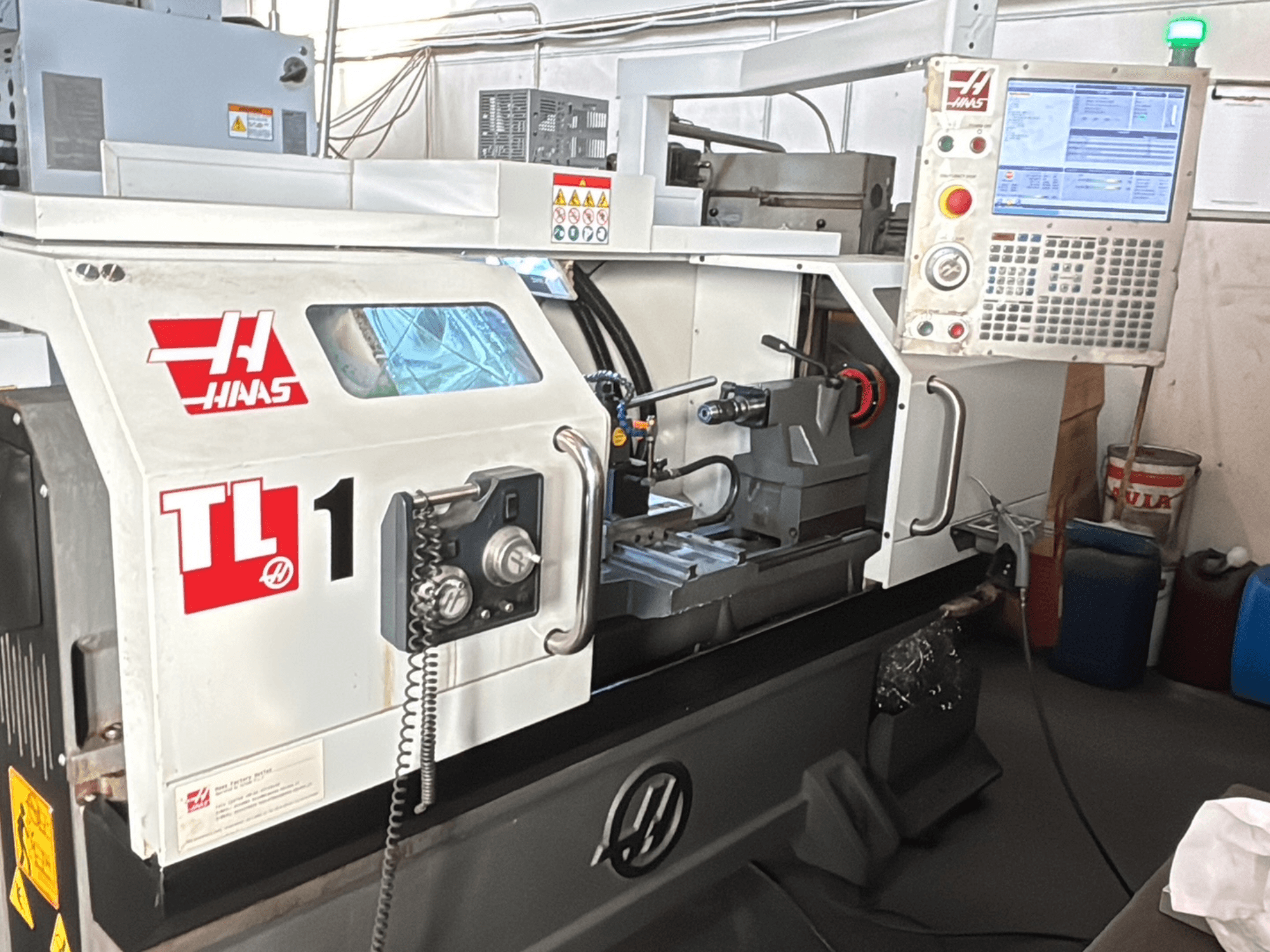 Haas TL-1 CNC-Drehmaschine, Vorderansicht, mit Bedienfeld mit Display, Werkzeughalter und Sicherheitsschildern.