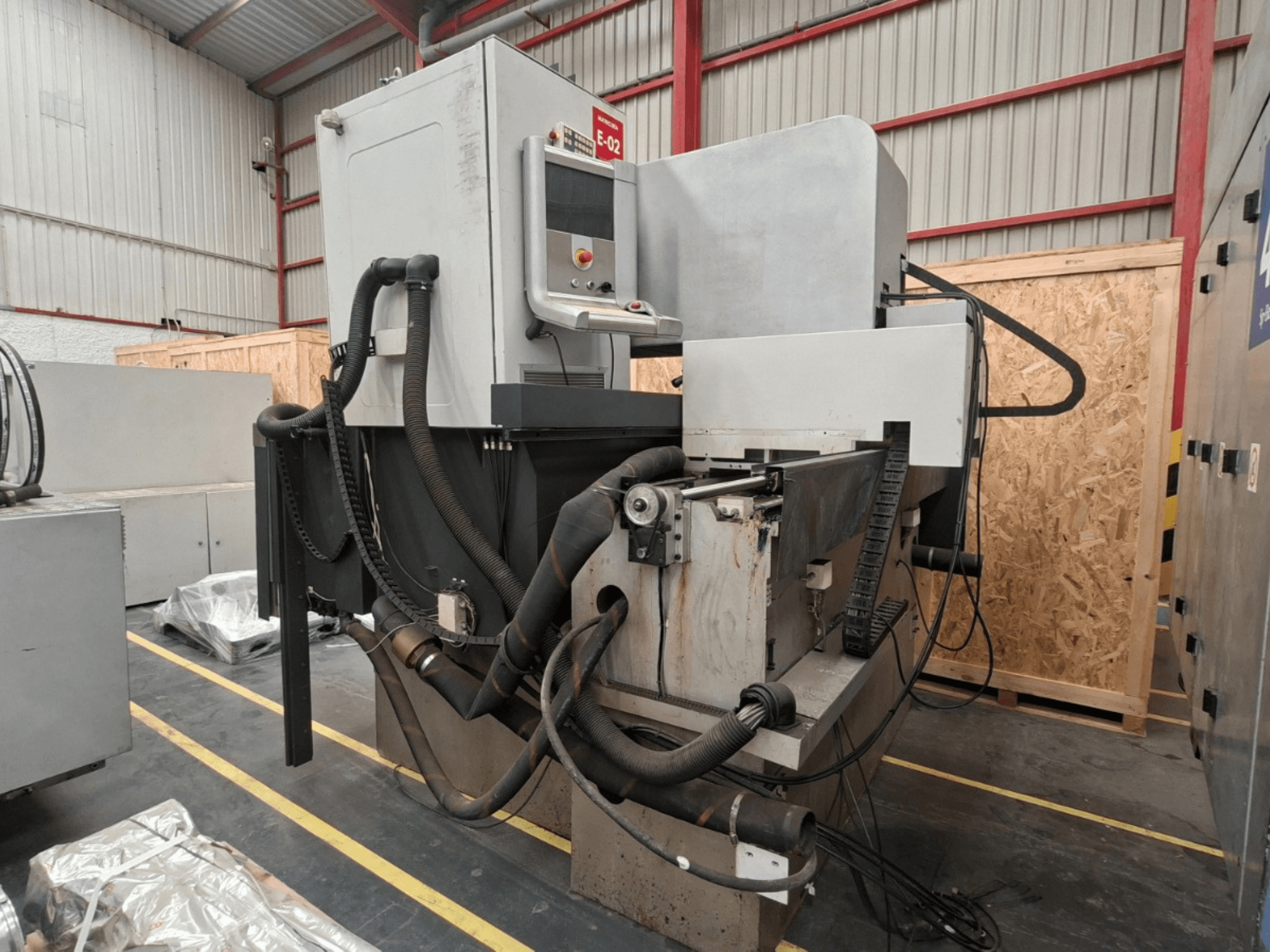 ONA NX7 Senkerodiermaschine, Seitenansicht mit Bedienfeld, Schläuchen und Bearbeitungsbereich in einer Werkstattumgebung.