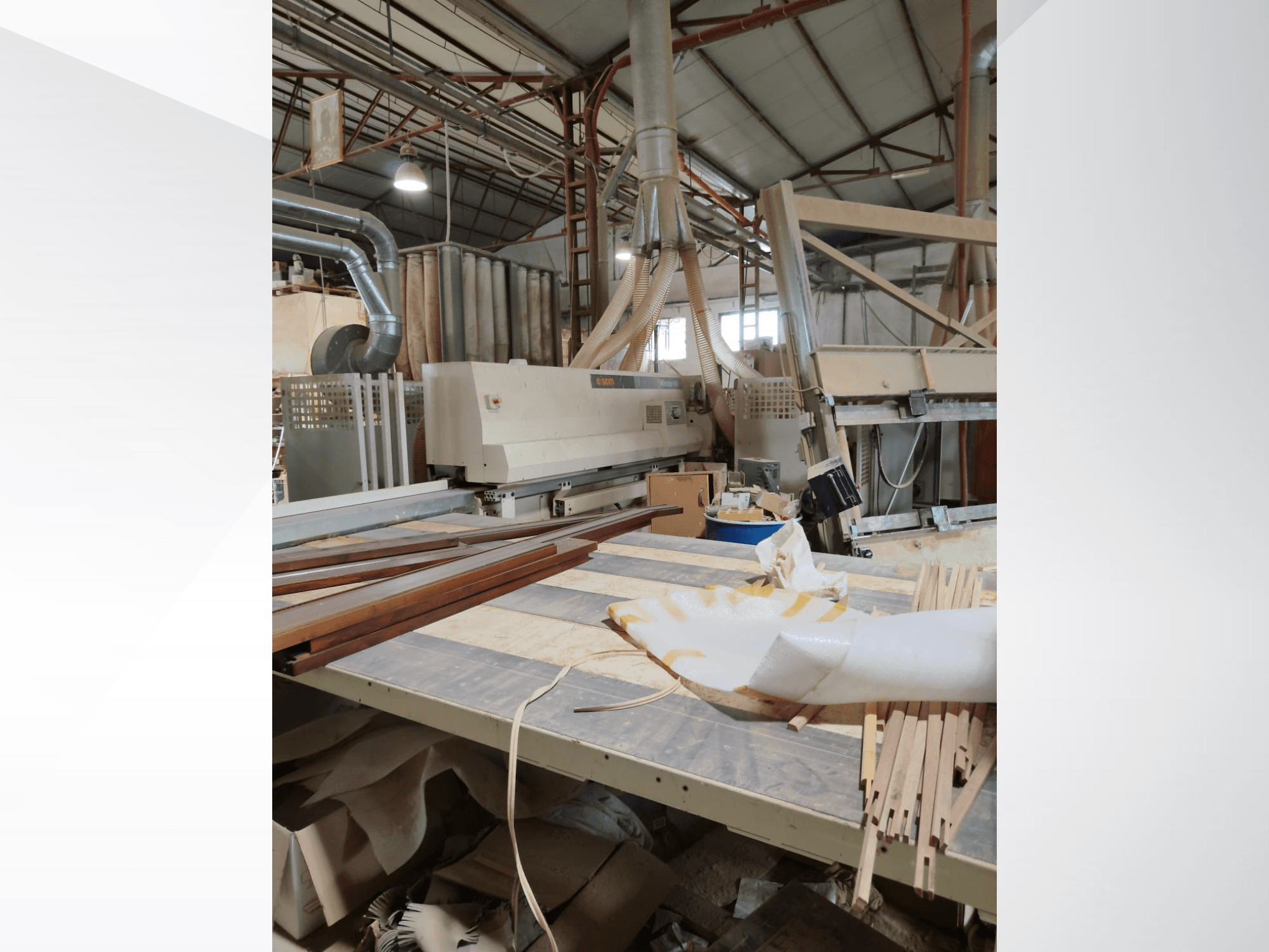 CNC-Holzbearbeitungszentrum SCM Windor60 in einer Werkstatt, von der Seite gesehen, mit Holzplatten und Staubabsauganlage.