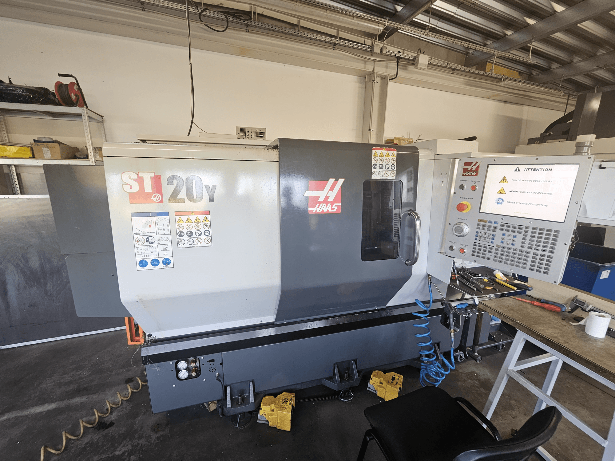 Haas ST-20Y CNC-Drehmaschine, Vorderansicht; mit Bedienfeld, Sicherheitshinweisen und Luftschlauchanschluss.