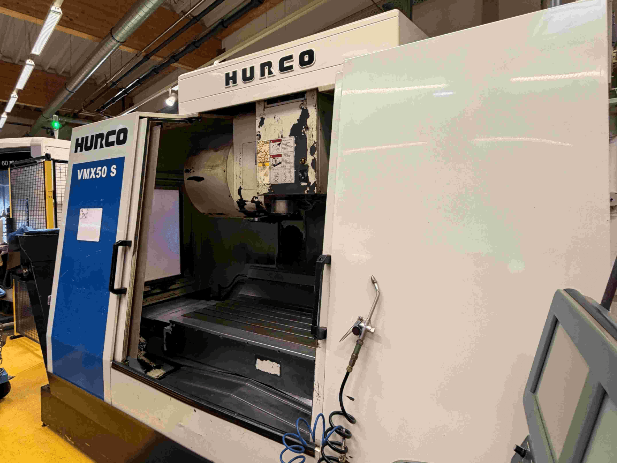 Hurco VMX50 S Vertikal-Bearbeitungszentrum, Seitenansicht, mit geöffneter Tür und Bedienfeld.