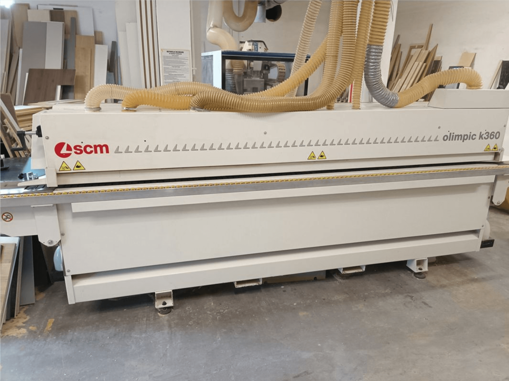 Kantenanleimmaschine SCM Olimpic K360 T-ER1 in einer Werkstatt, Vorderansicht mit Staubabsaugschläuchen und Warnhinweisen.