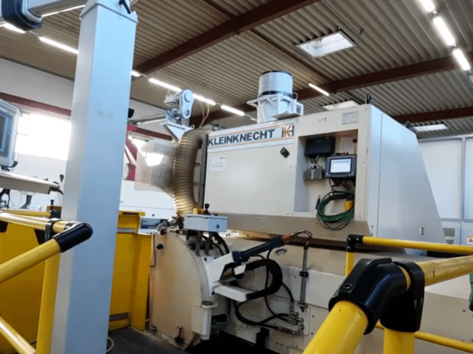 Rundschleifmaschine WALDRICH KLEINKNECHT WS III C 6.00 X 5000, dargestellt in der Seitenansicht, mit Bedienpult und Absauganlage.