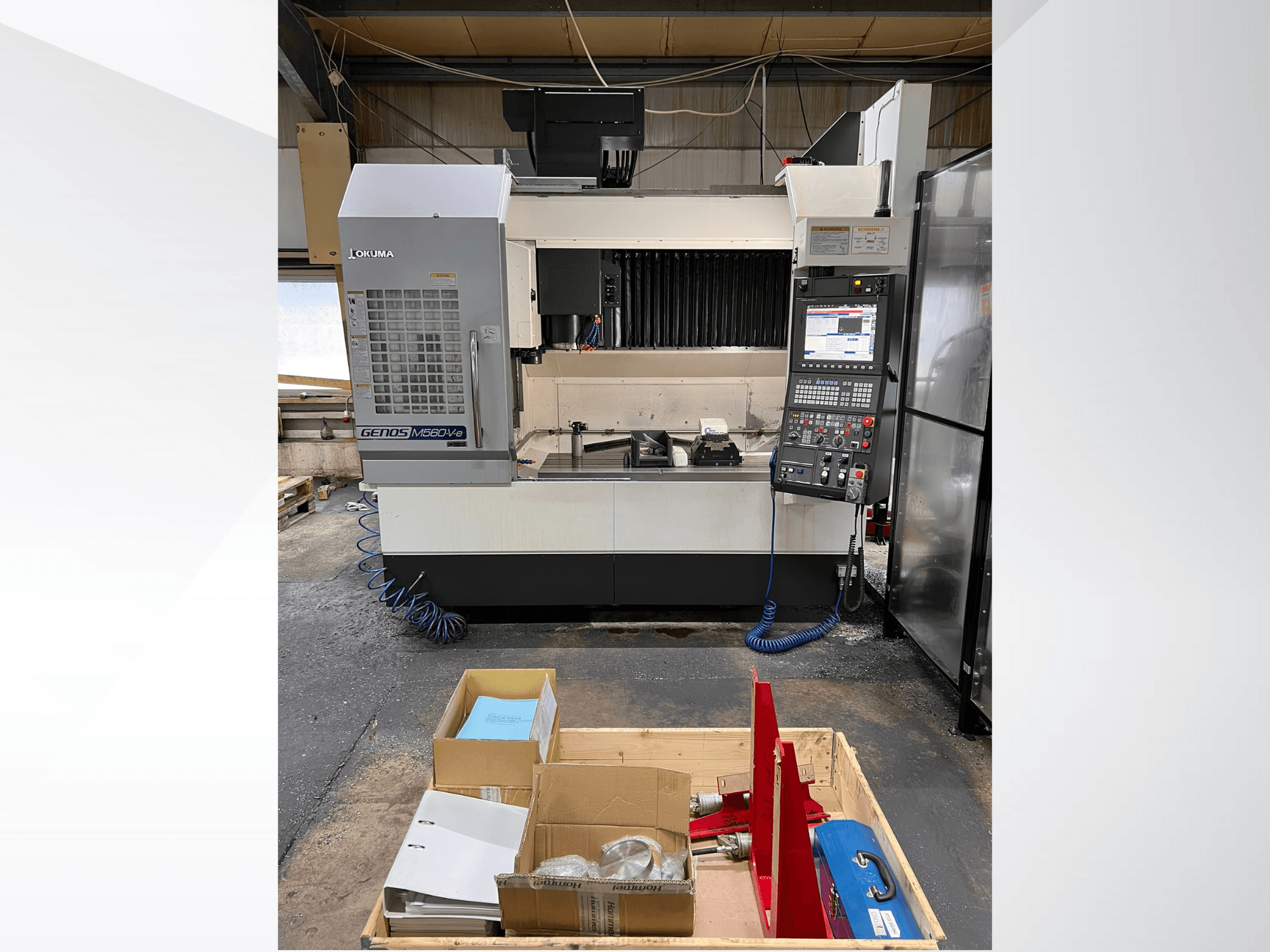 Okuma GENOS M460V-5 Vertikal-Bearbeitungszentrum, Vorderansicht, mit sichtbarem Bedienfeld und Werkzeugen auf dem Arbeitstisch.