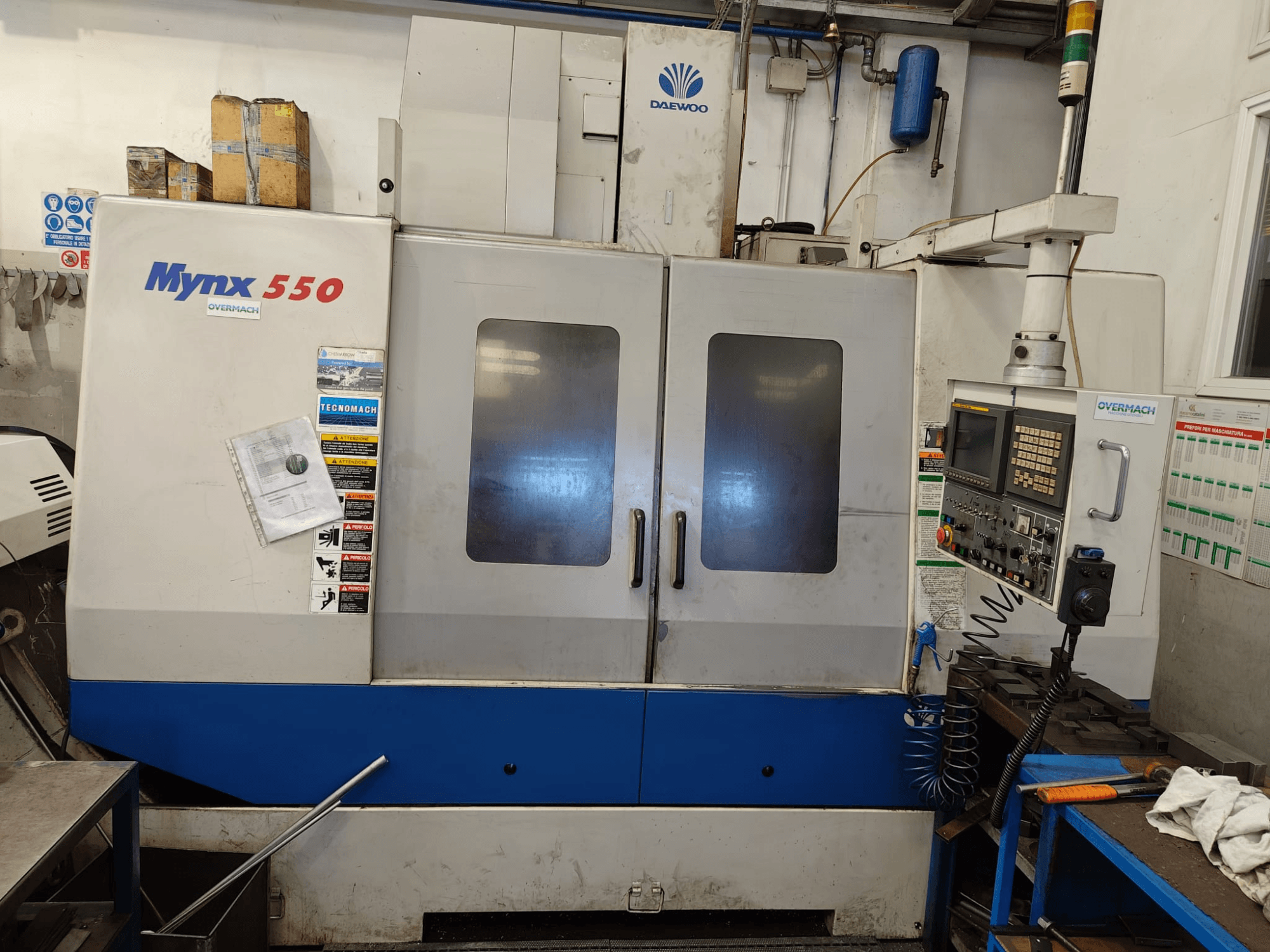 Vertikales Bearbeitungszentrum DAEWOO MYNX 550, Vorderansicht, mit Bedienfeld, zwei großen Türen und Sicherheitsaufklebern.