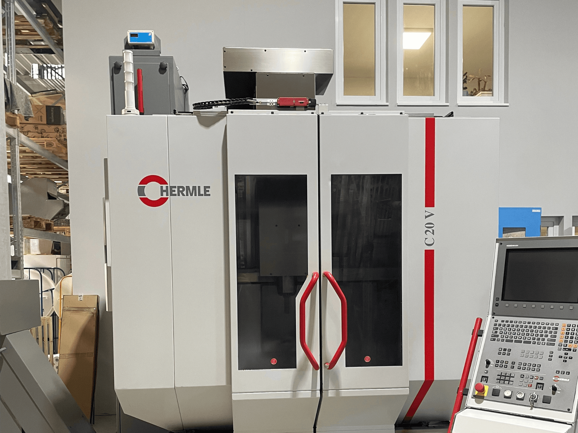 CNC-Maschine Chermle C20 V, Vorderansicht, mit Bedienfeld und roten Griffen; Industriedesign mit großen Glastüren.