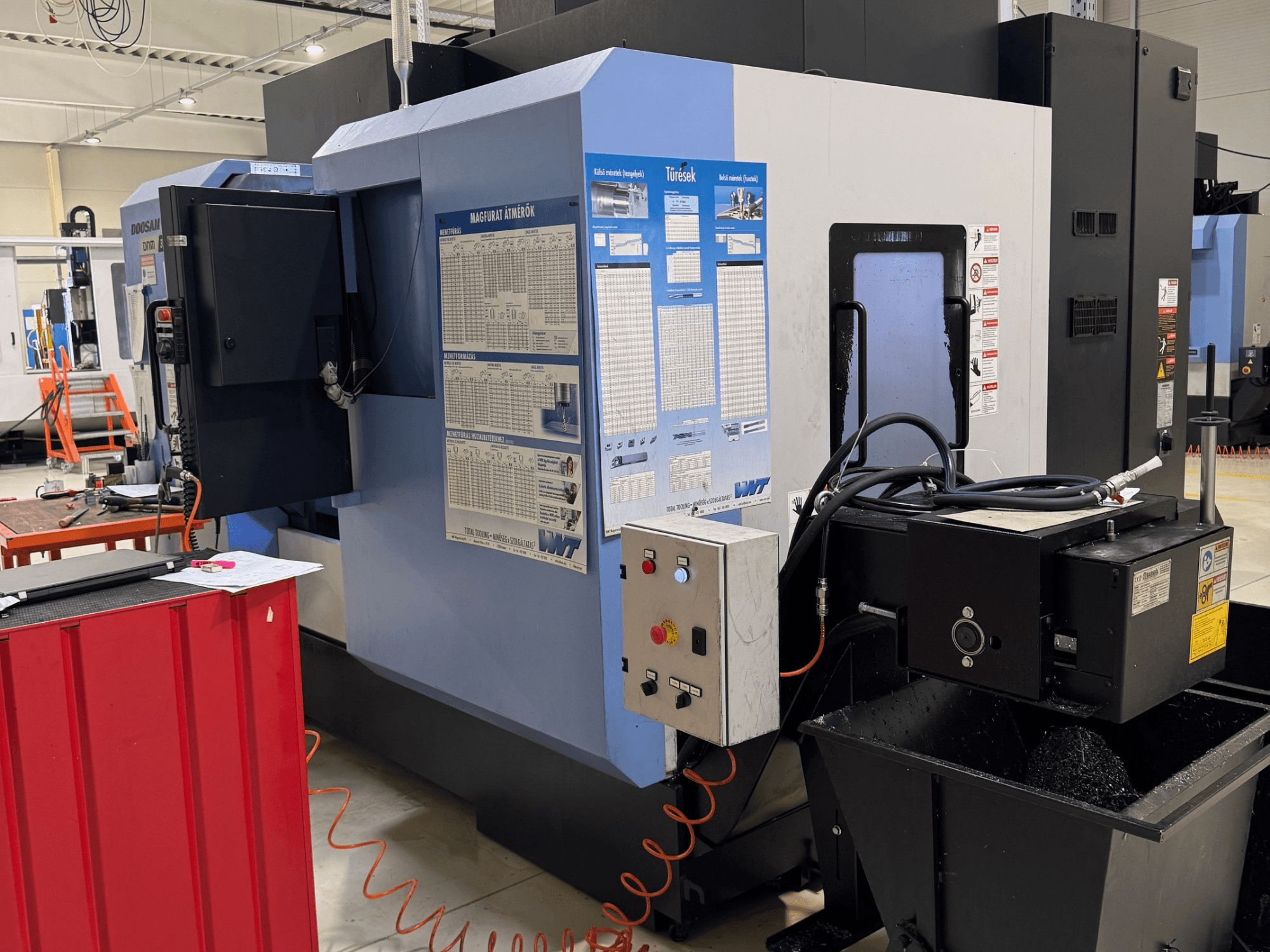 DOOSAN DNM350/5AX Fräs-Dreh-Zentrum, Seitenansicht mit Bedienfeld und Kühlmitteltank, wobei die Funktionsdetails zu erkennen sind.
