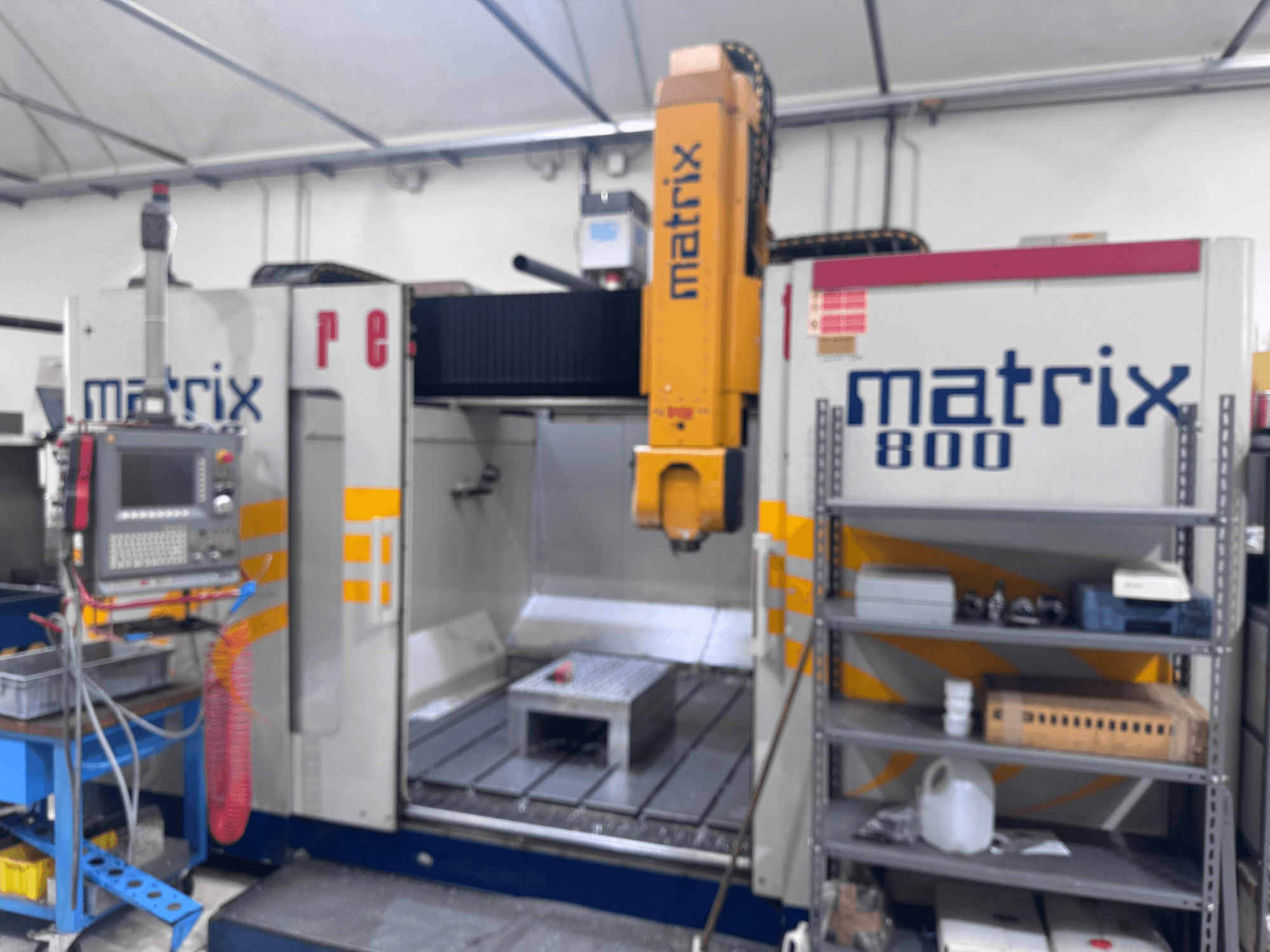 Matrix 800 CNC-Maschine in einer Werkstattansicht mit Bedienfeld, Werkzeugen und Arbeitstisch mit verschiedenen Objekten.