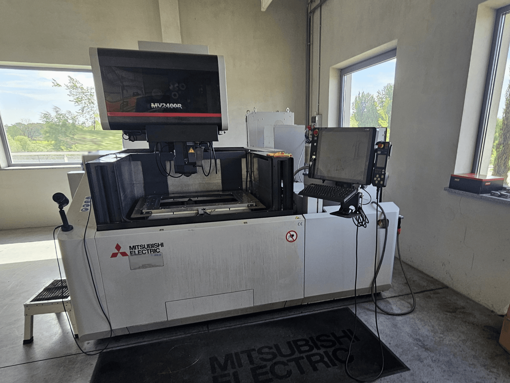 Mitsubishi MV2400R Drahterodiermaschine in einer Werkstatt, mit Touchscreen-Bedienfeld und Arbeitsbereich.