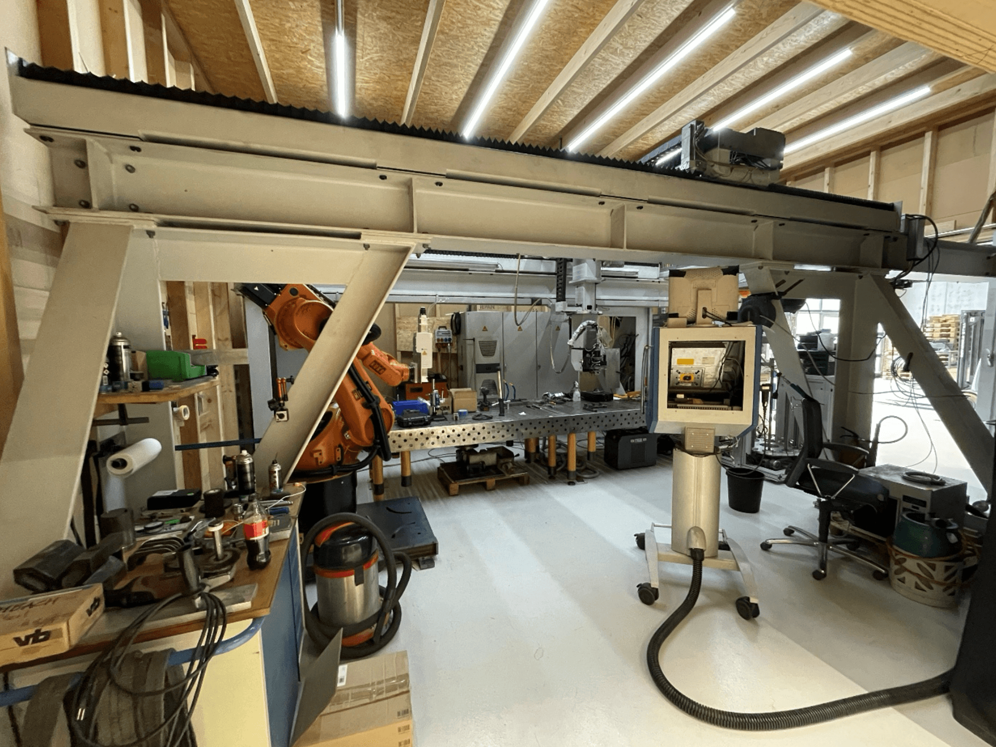 Stiefelmayer Laserhärtenanlage, Vorderansicht, mit Roboterarm und Bedienfeld in einer Werkstattumgebung.