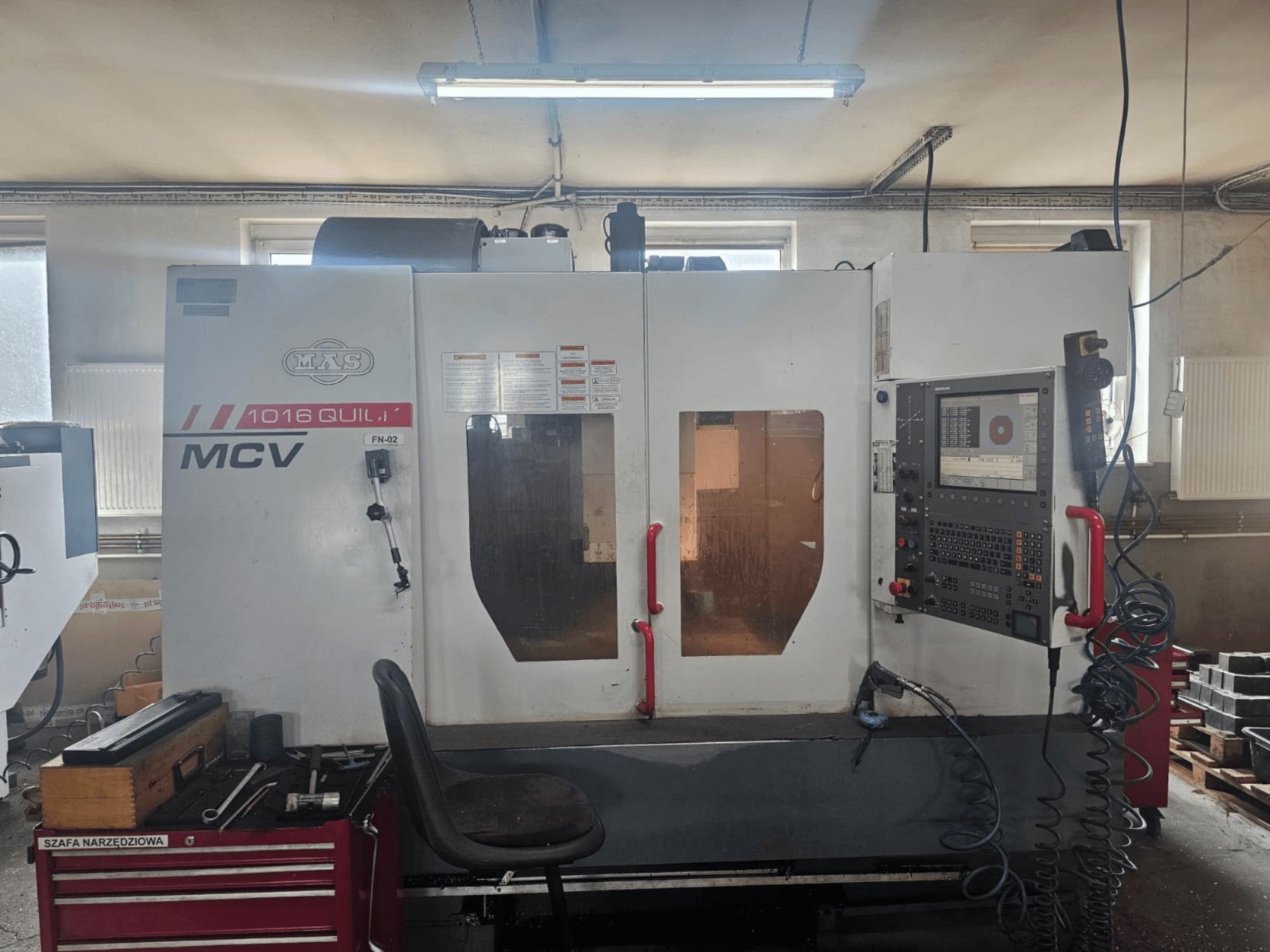 MVS MCV 1016 QUILL CNC-Maschine, Vorderansicht, mit Bedienfeld, Werkzeugschublade und Arbeitsbereich mit Werkzeugen.