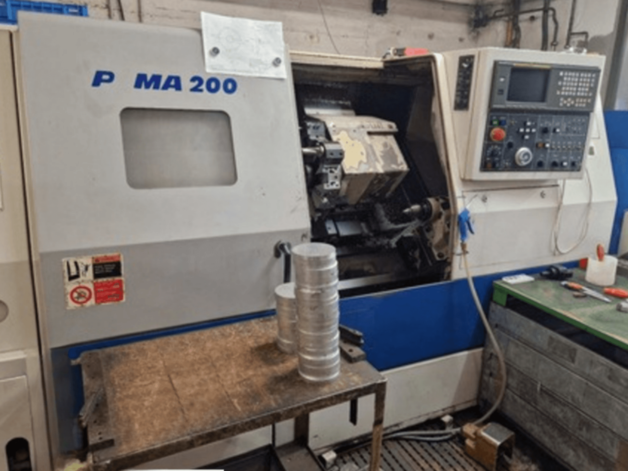 DAEWOO EcoTurn 200 Horizontaldrehmaschine, Vorderansicht, mit Aluminiumwerkstücken auf einem Tisch, Bedienfeld sichtbar.