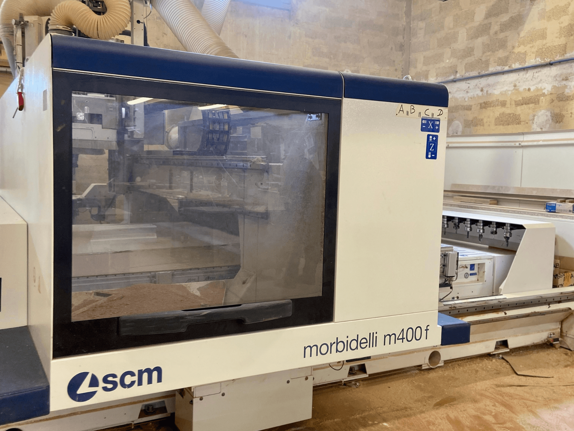 SCM Morbidelli M400F CNC-Maschine, Vorderansicht, mit Bedienfeld und sichtbarem Sägemehl auf dem Boden.