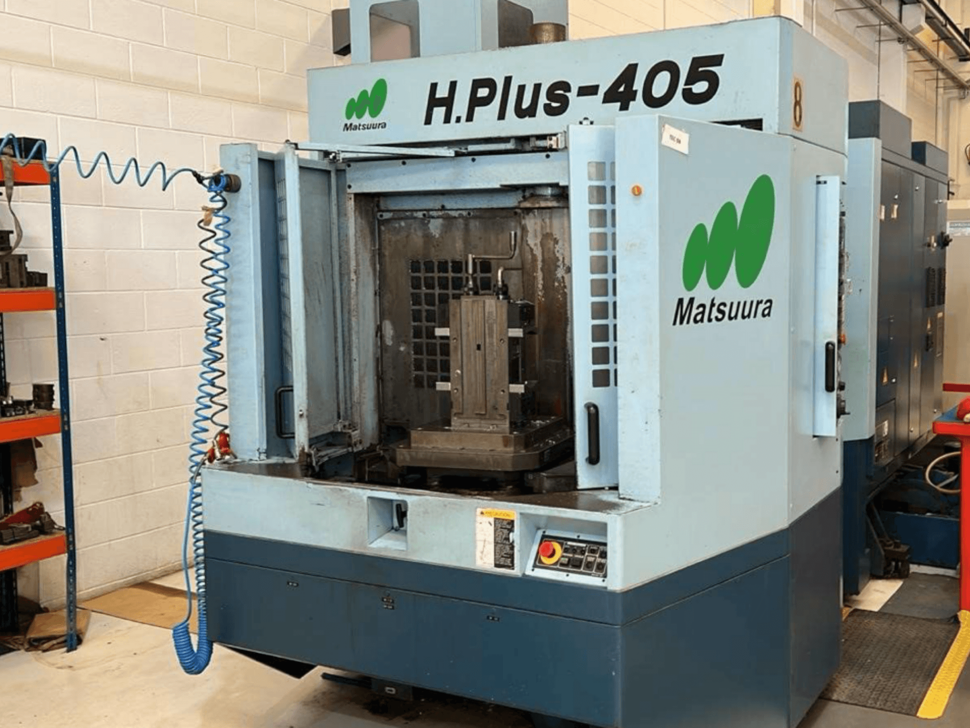 Vorderansicht eines horizontalen Bearbeitungszentrums vom Typ Matsuura H.Plus 405 mit geöffneter Tür, die den Arbeitsbereich und das Bedienfeld zeigt.