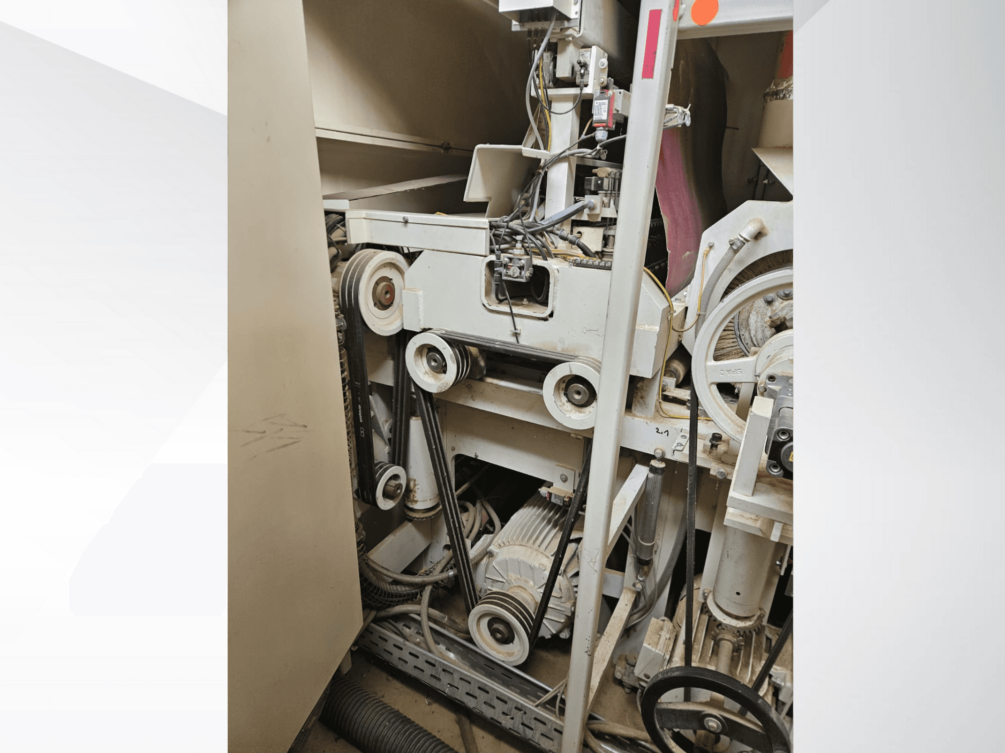 Innenraum einer Industriemaschine mit Riemen und Riemenscheiben, mit Motor und Verkabelung, von der Seite gesehen.