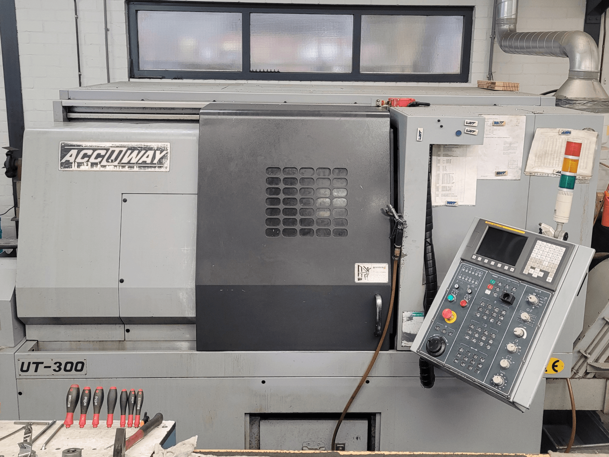 Die CNC-Maschine Accuway UT-300 in der Vorderansicht mit Bedienfeld und verschiedenen Tasten in einer Werkstattumgebung.