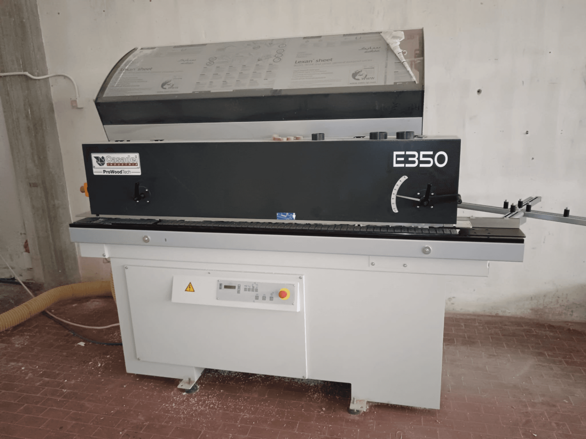 Cesaroli ProWoodtech E350, Seitenansicht einer Holzbearbeitungsmaschine mit Bedienfeld und Staubauffangbehälter, montiert auf einem weißen Sockel.