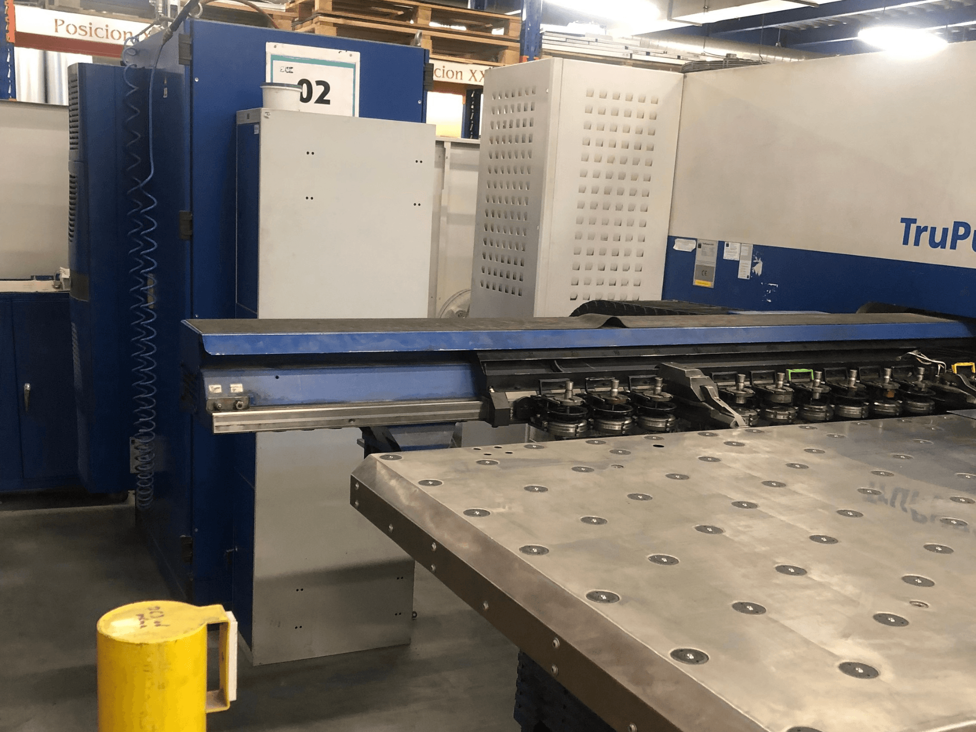 CNC-Stanzmaschine TRUMPF TruPunch 5000, Vorderansicht mit Werkzeugrevolver und Bedienfeld, daneben ein Metallarbeitstisch.