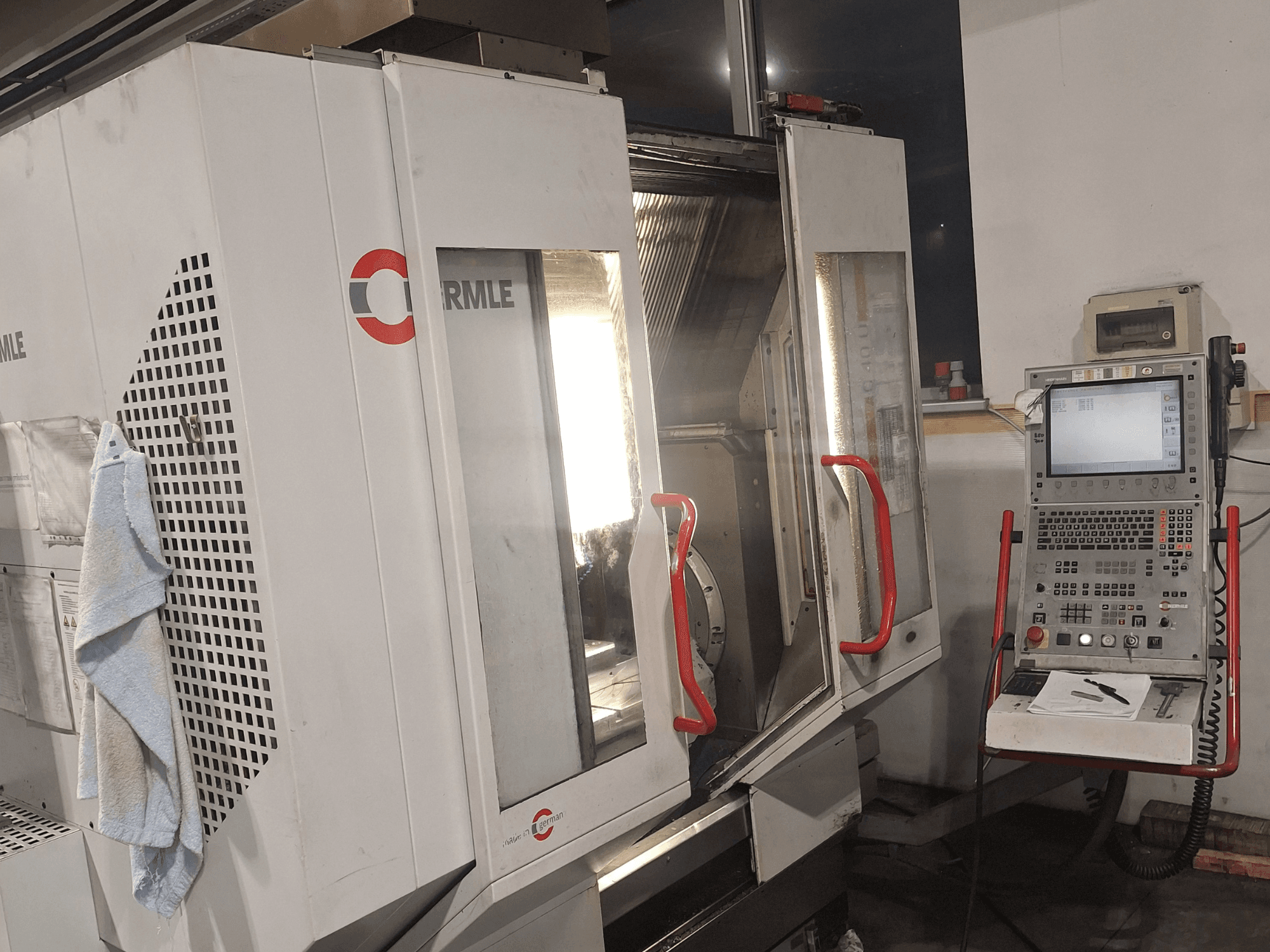 CNC-Maschine der Marke Cormile, Vorderansicht mit teilweise geöffneten Türen und Bedienfeld mit Bildschirm und Tasten.